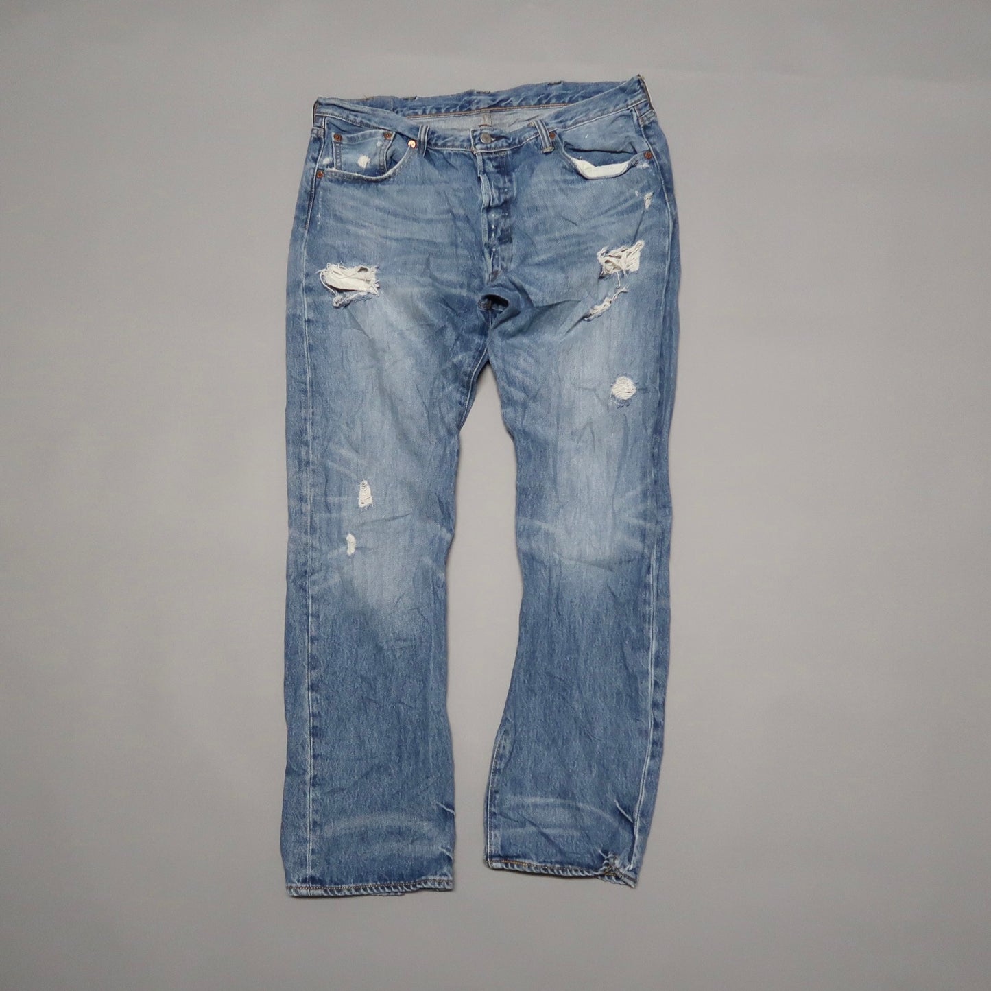 Distressed blue jeans with several ripped patches.