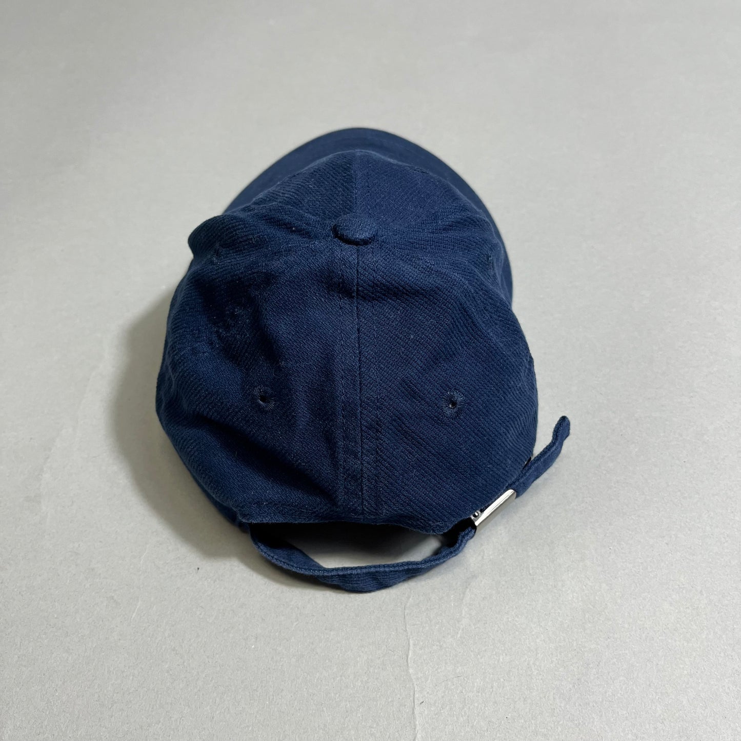 Navy blue baseball cap with adjustable strap on gray background.