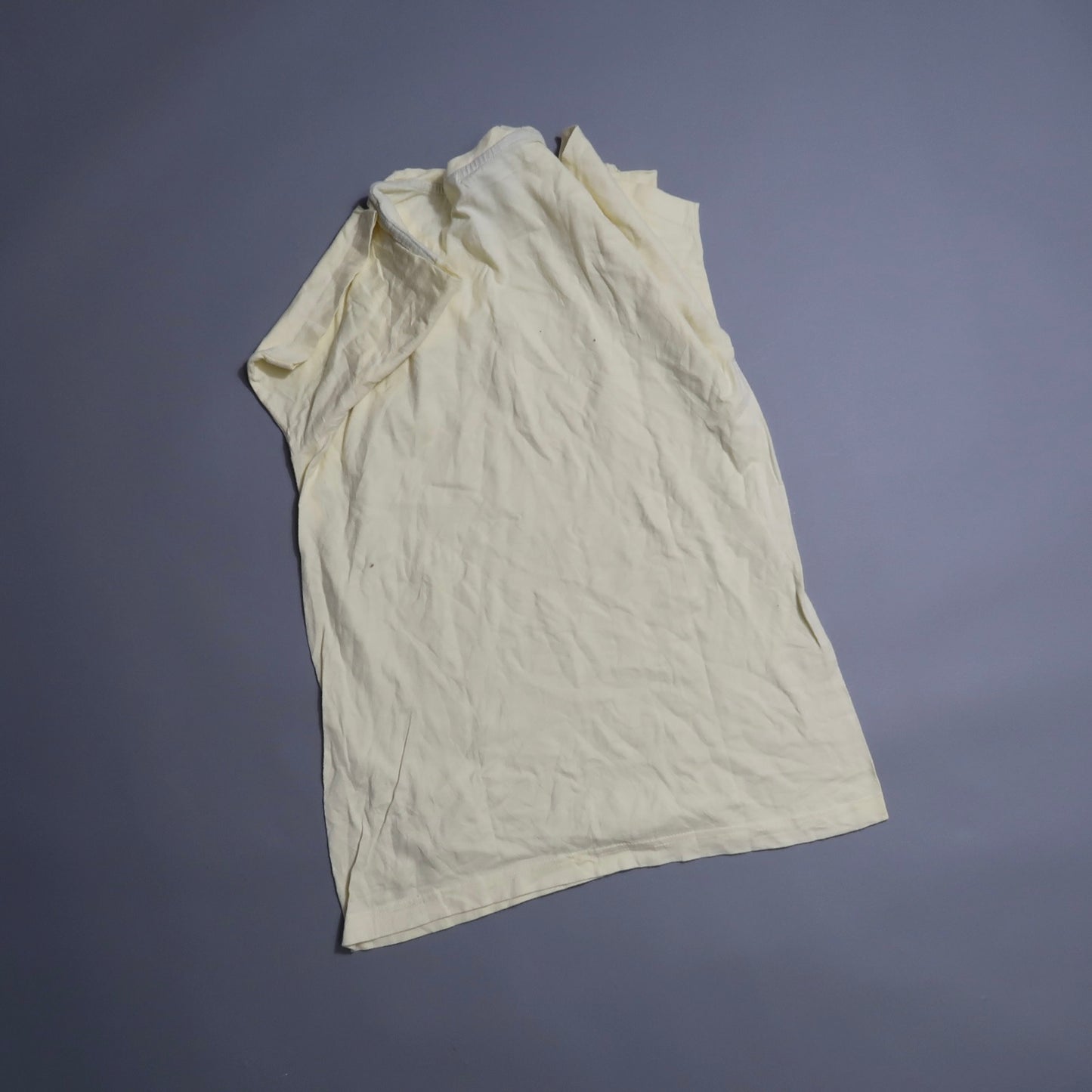 Wrinkled white T-shirt on a gray background.