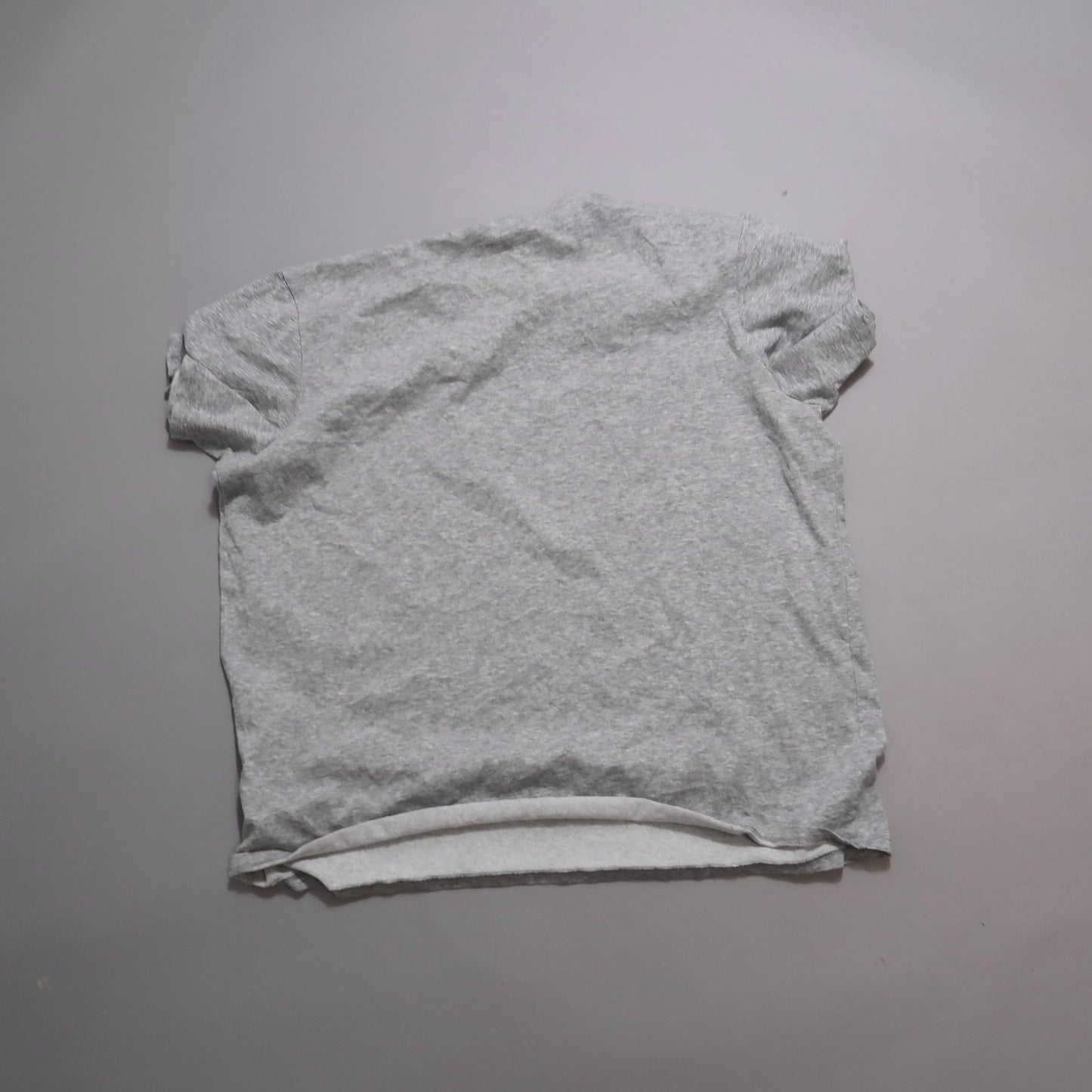 Gray T-shirt laid flat on a plain surface.