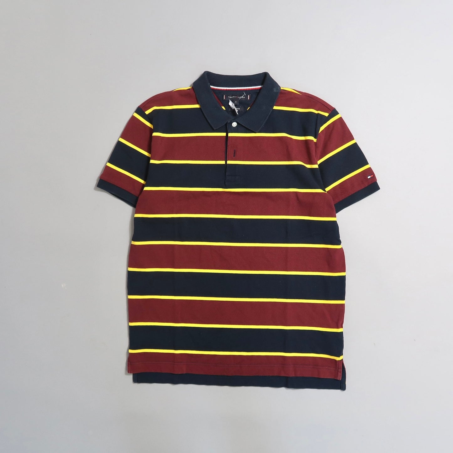 Striped polo shirt with maroon and navy hues, yellow accents.