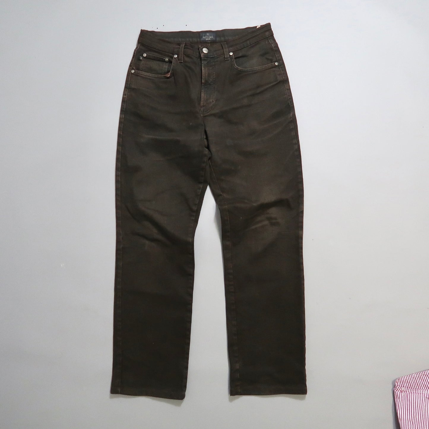 Dark brown high-waisted jeans on a light gray background.