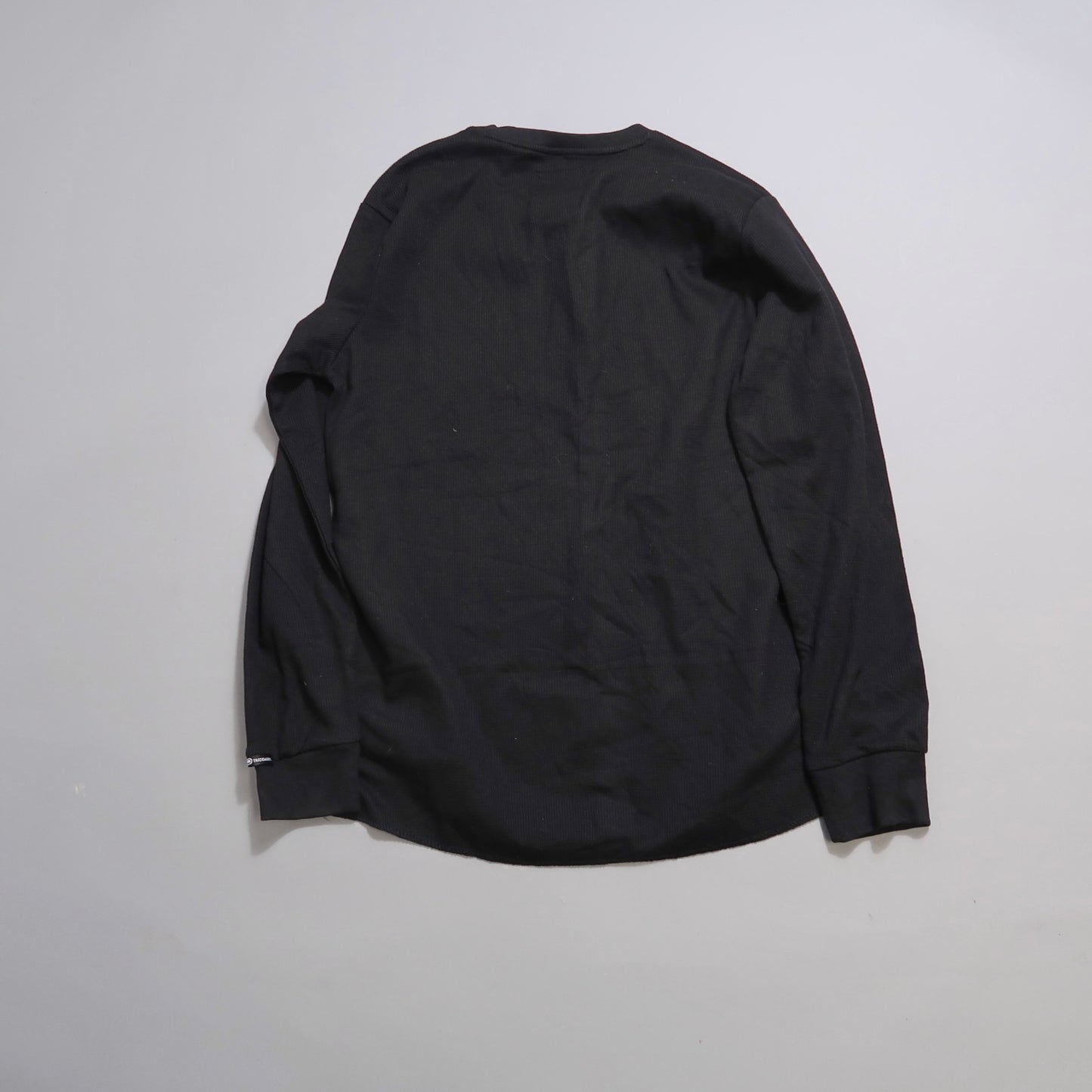Black long-sleeve shirt laid flat, back view.