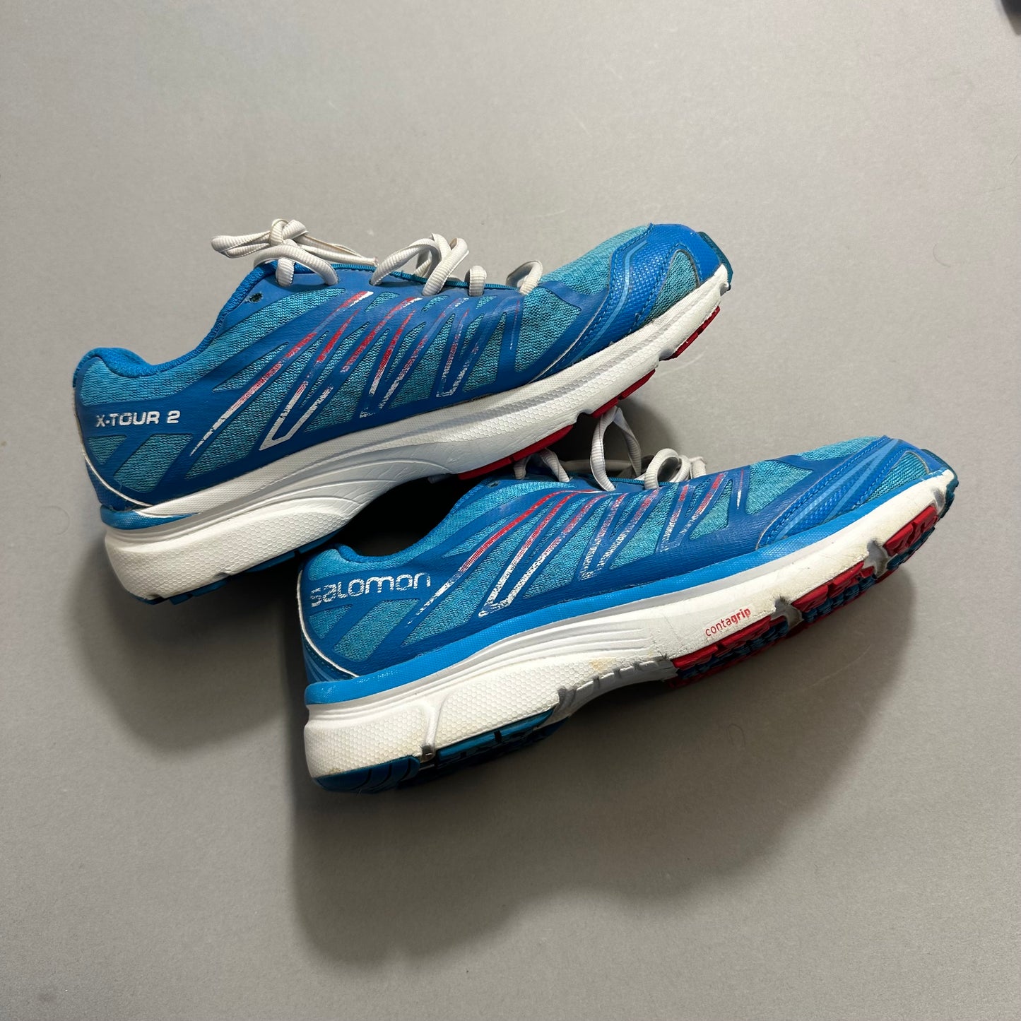 Blue running shoes with white soles on a gray background.