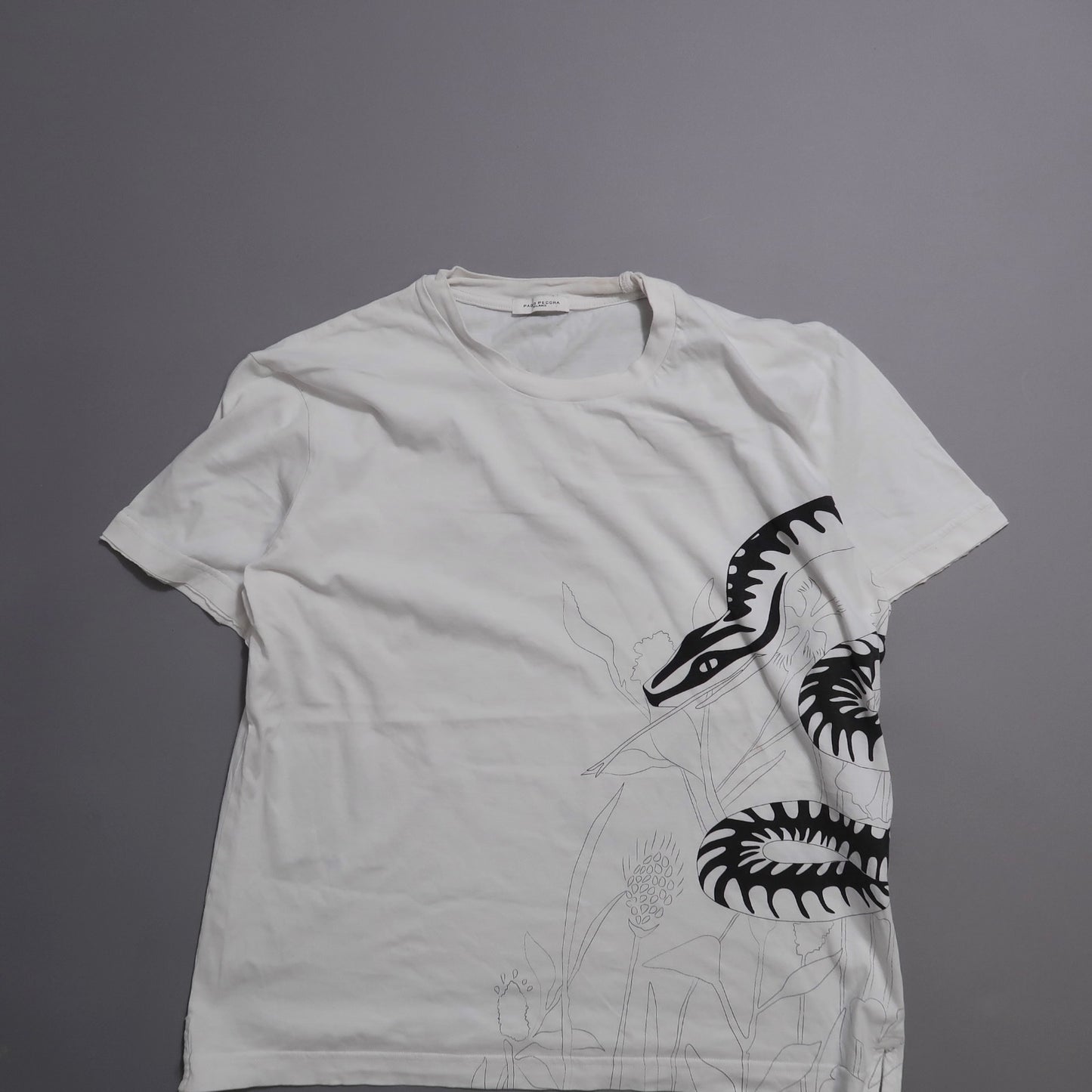 White T-shirt with black snake graphic and plant outlines.