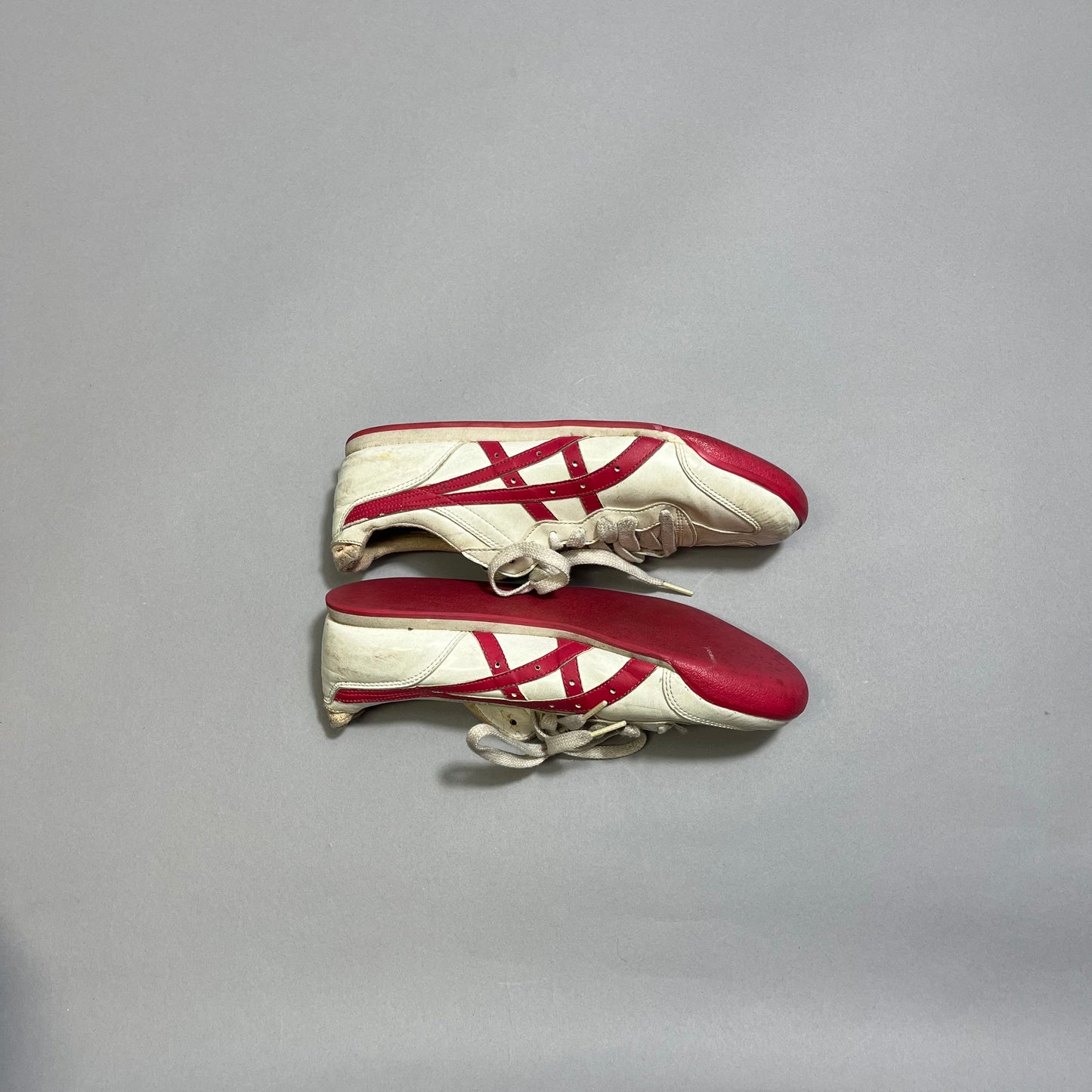 White sneakers with red stripes and accents on a gray background.