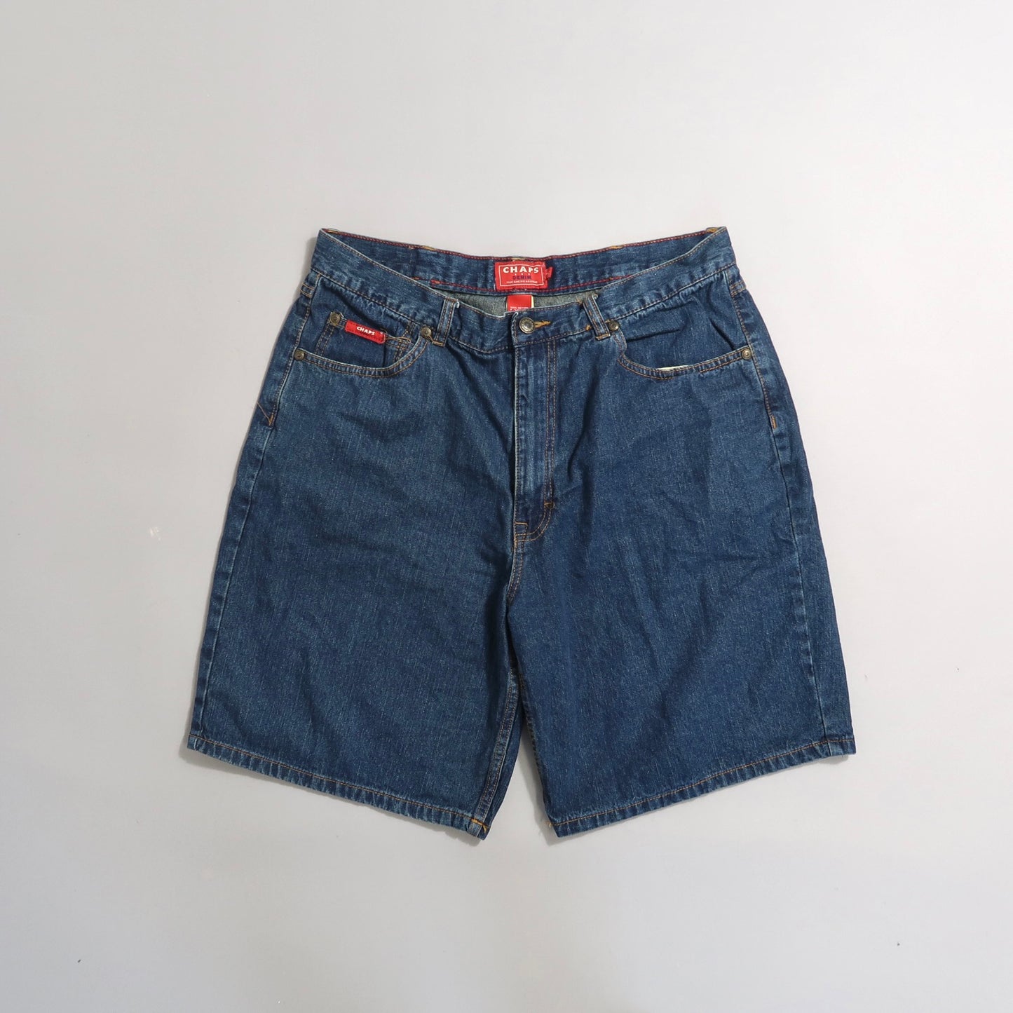 Blue denim shorts with red label on gray background.