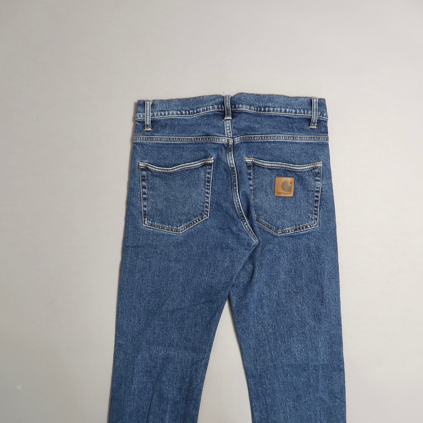 Blue jeans with back pockets and a brown logo patch on the right pocket.