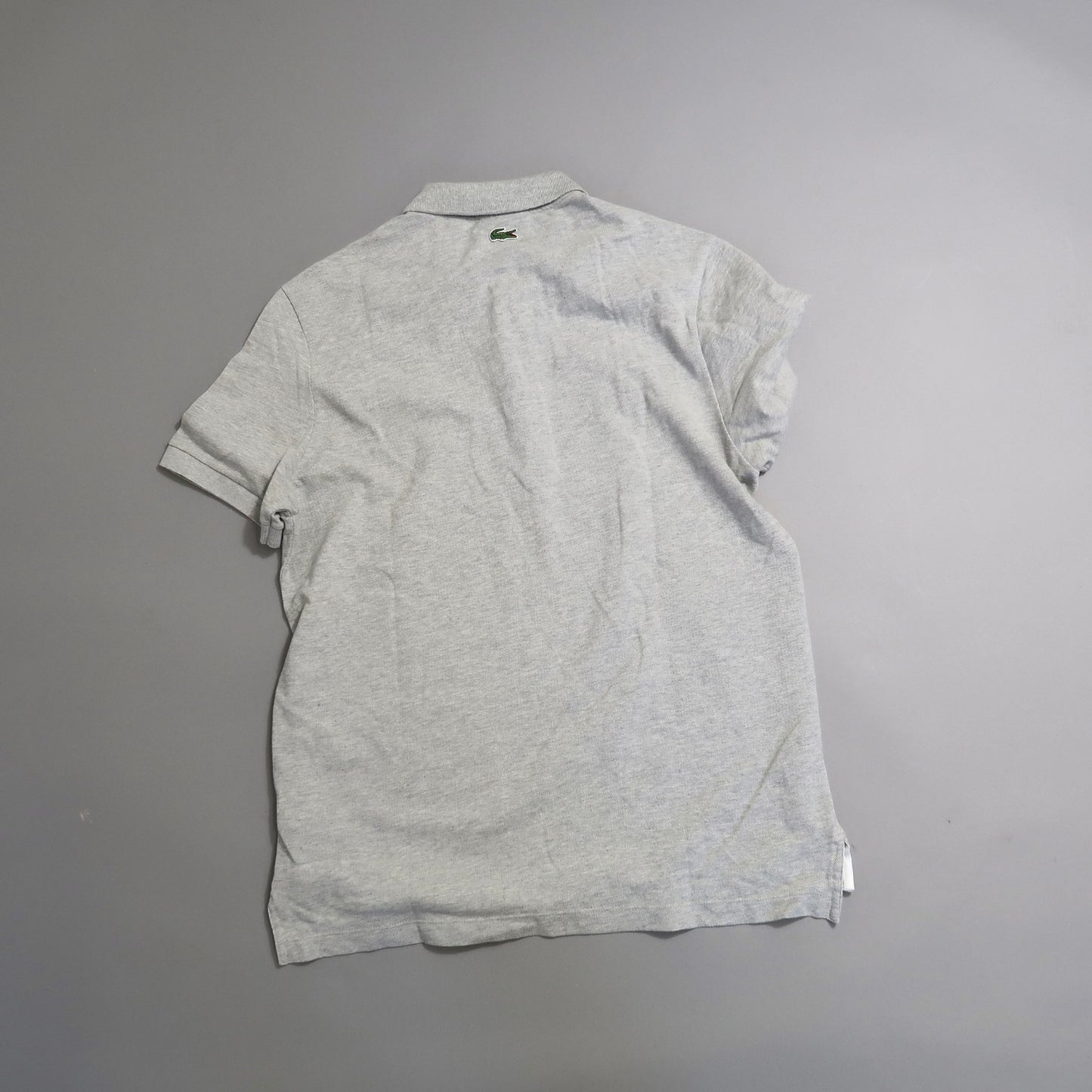 Gray polo shirt with logo on the back, laid flat on a surface.