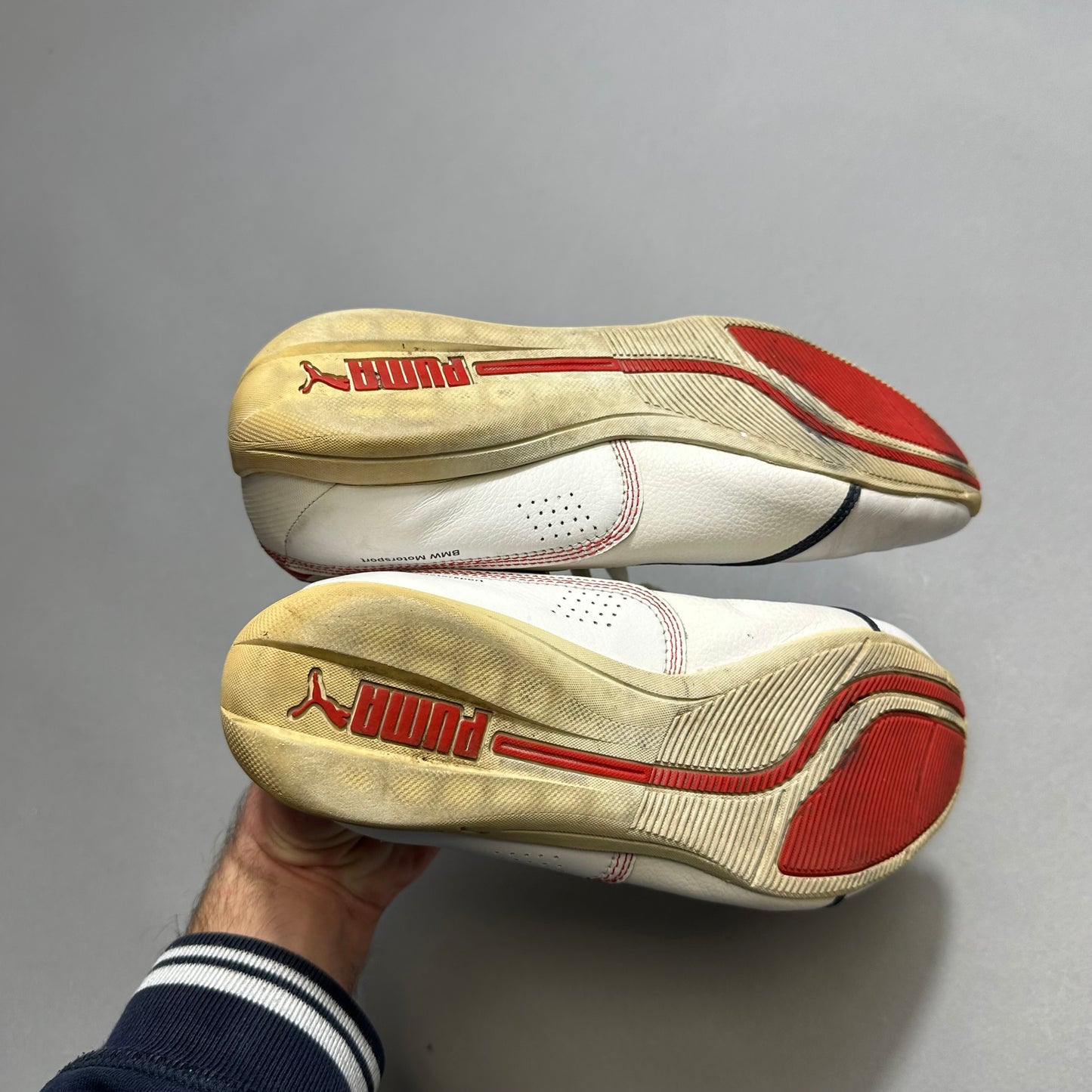 White Puma sneakers with red details and logo on soles.