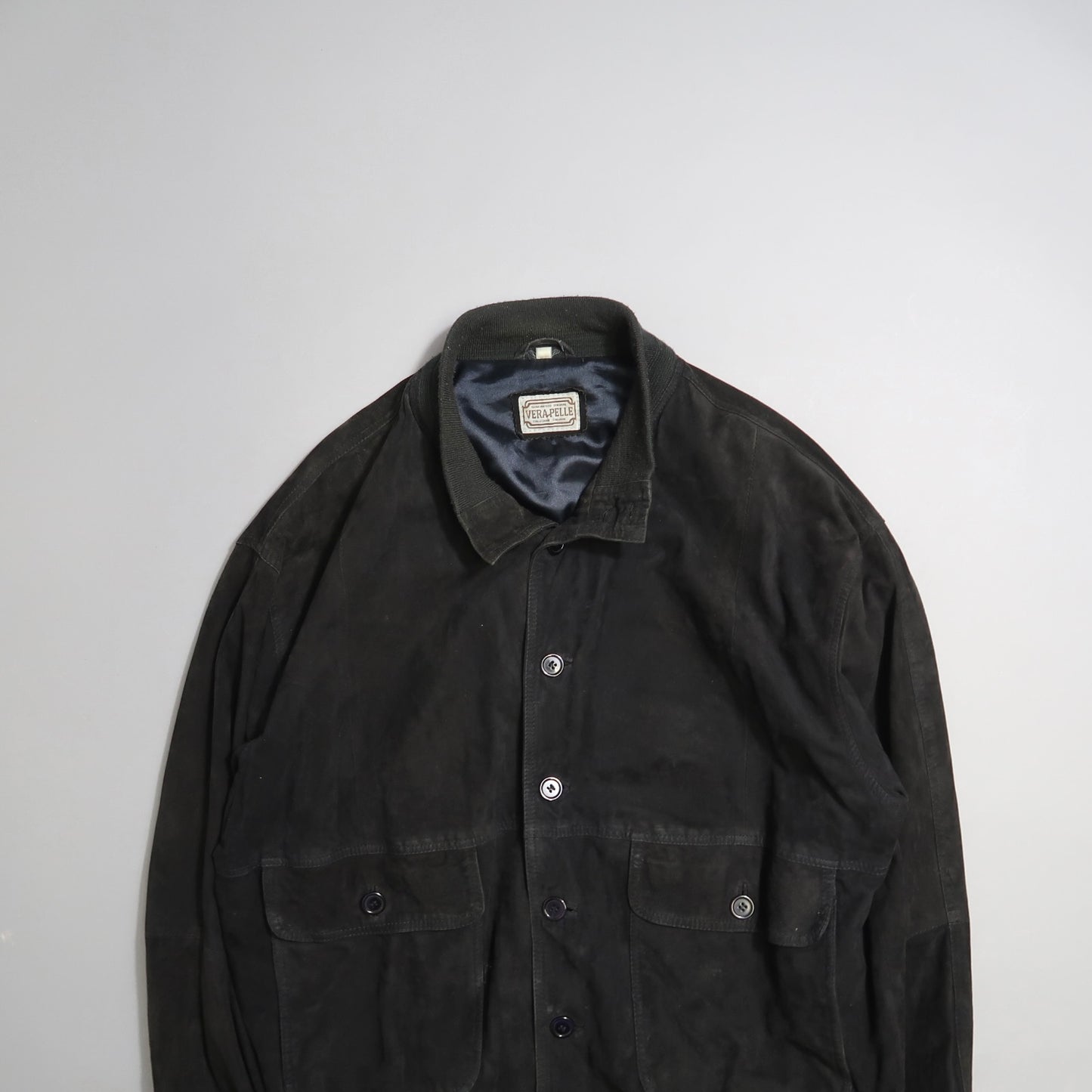 Dark buttoned leather jacket with two front pockets on a light background.