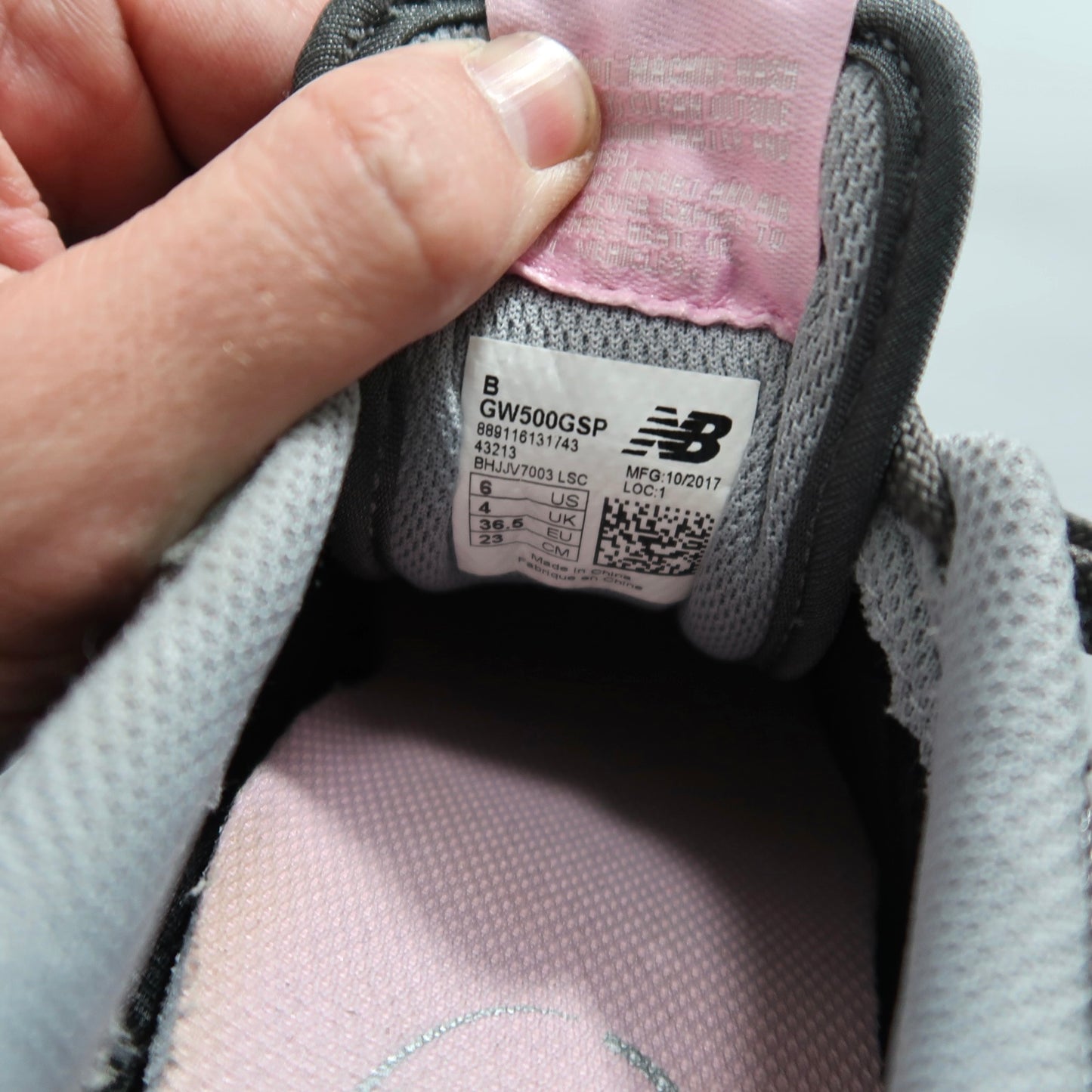 Hand holding a shoe tongue, showing the New Balance size label.