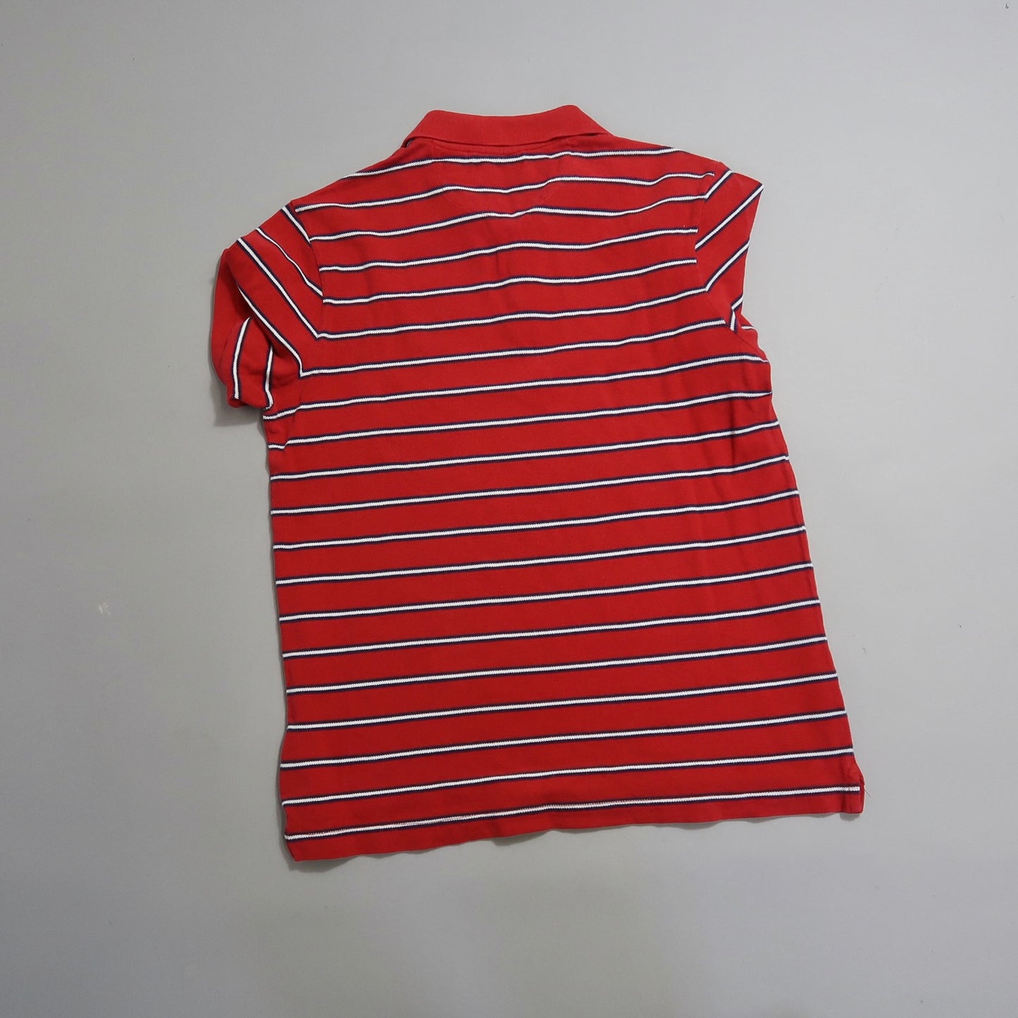 Red and white horizontally striped short-sleeve shirt on plain background.