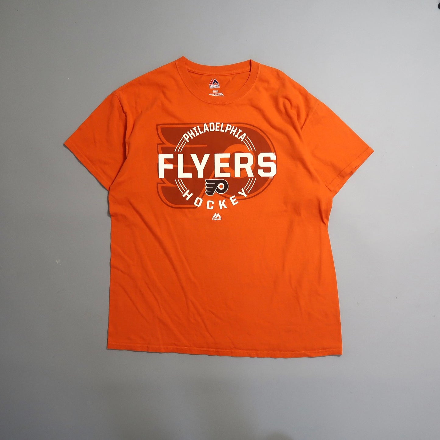 Orange Philadelphia Flyers hockey T-shirt on a gray background.