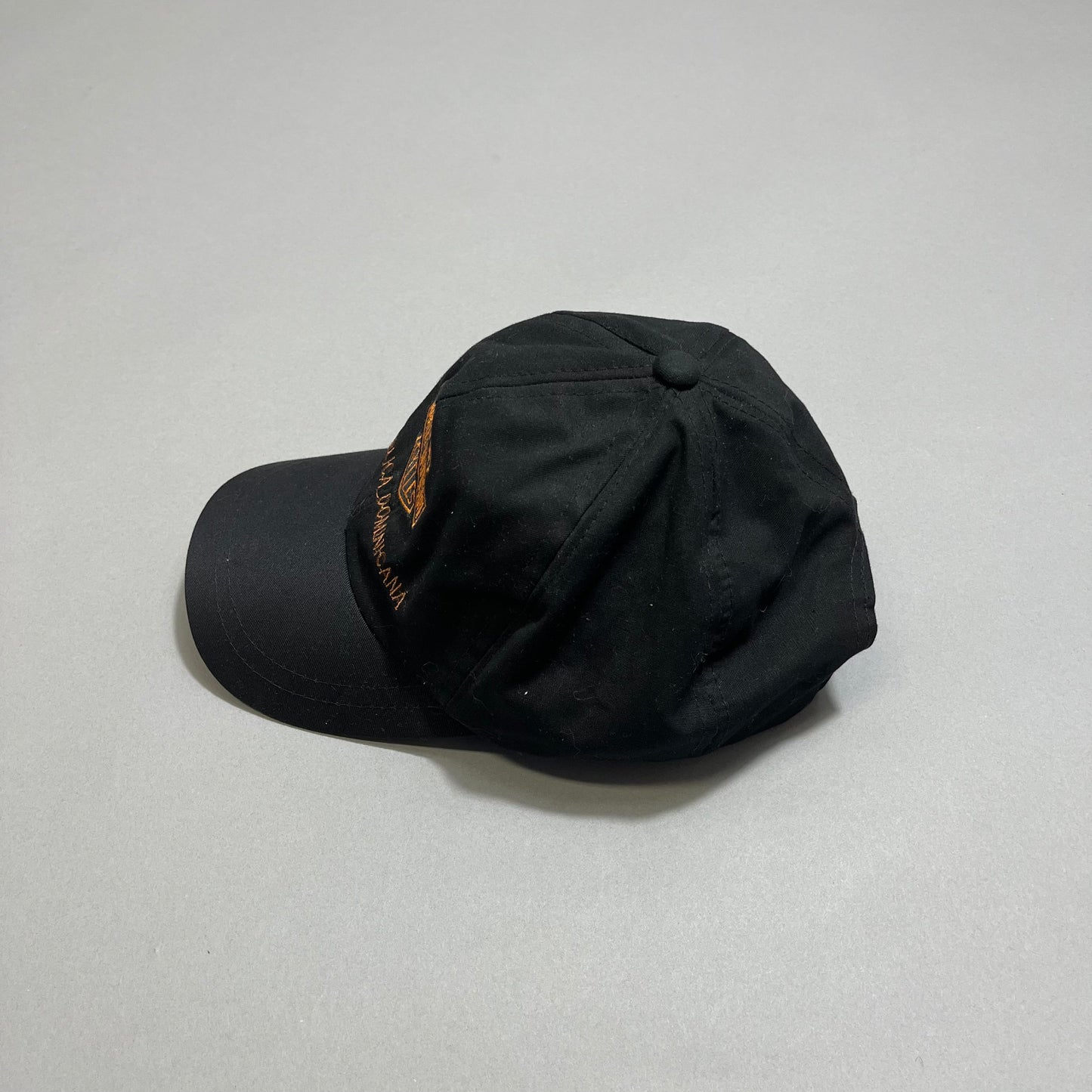 Black baseball cap with embroidery on a plain gray background.