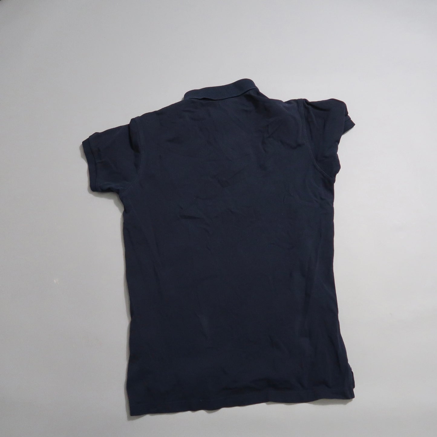 Navy blue polo shirt displayed on a white surface, back view.