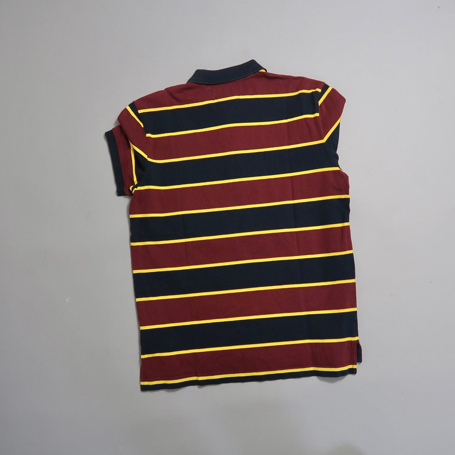 Maroon and navy striped shirt with yellow lines on a flat surface.