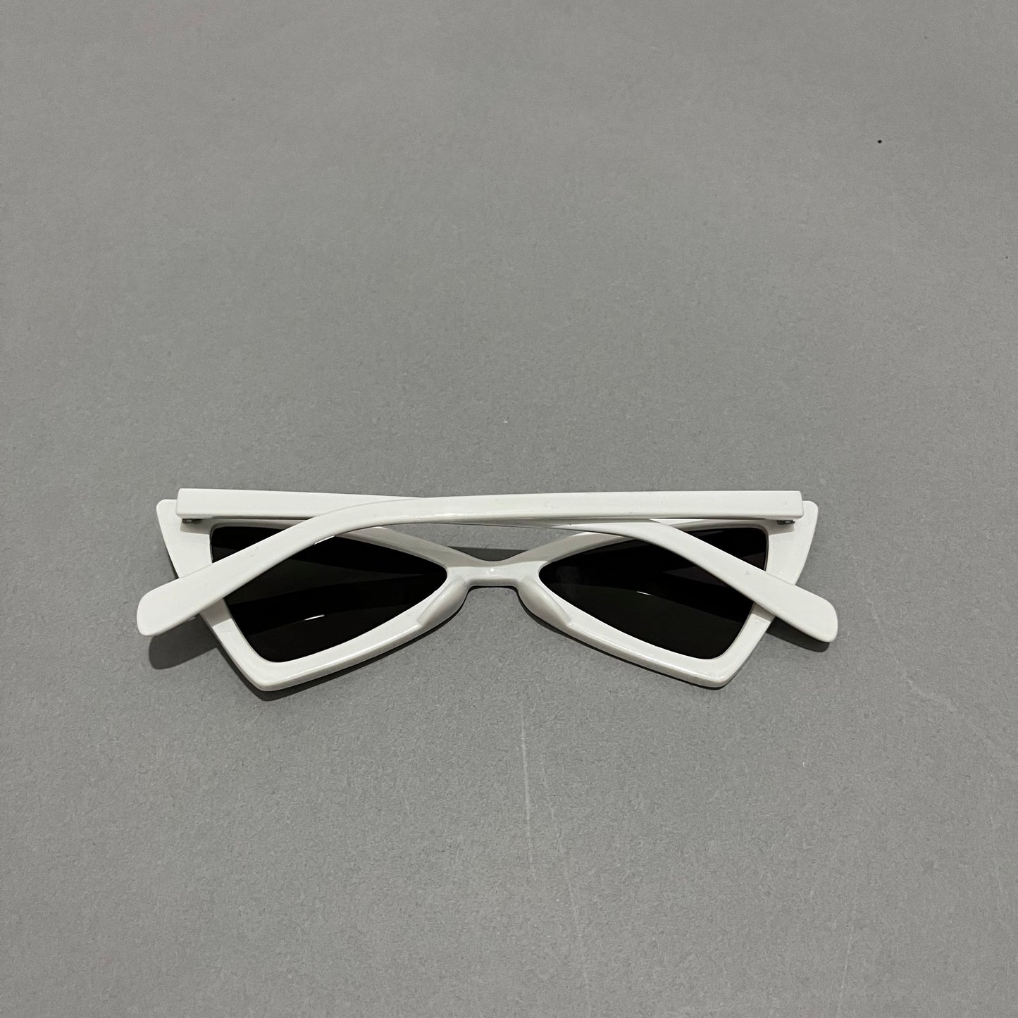 White cat-eye sunglasses on a gray surface.