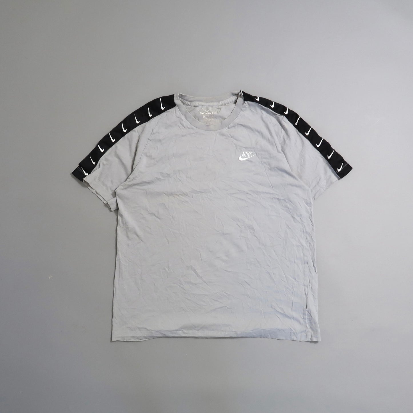 Gray Nike shirt with black sleeve accents featuring white swooshes.