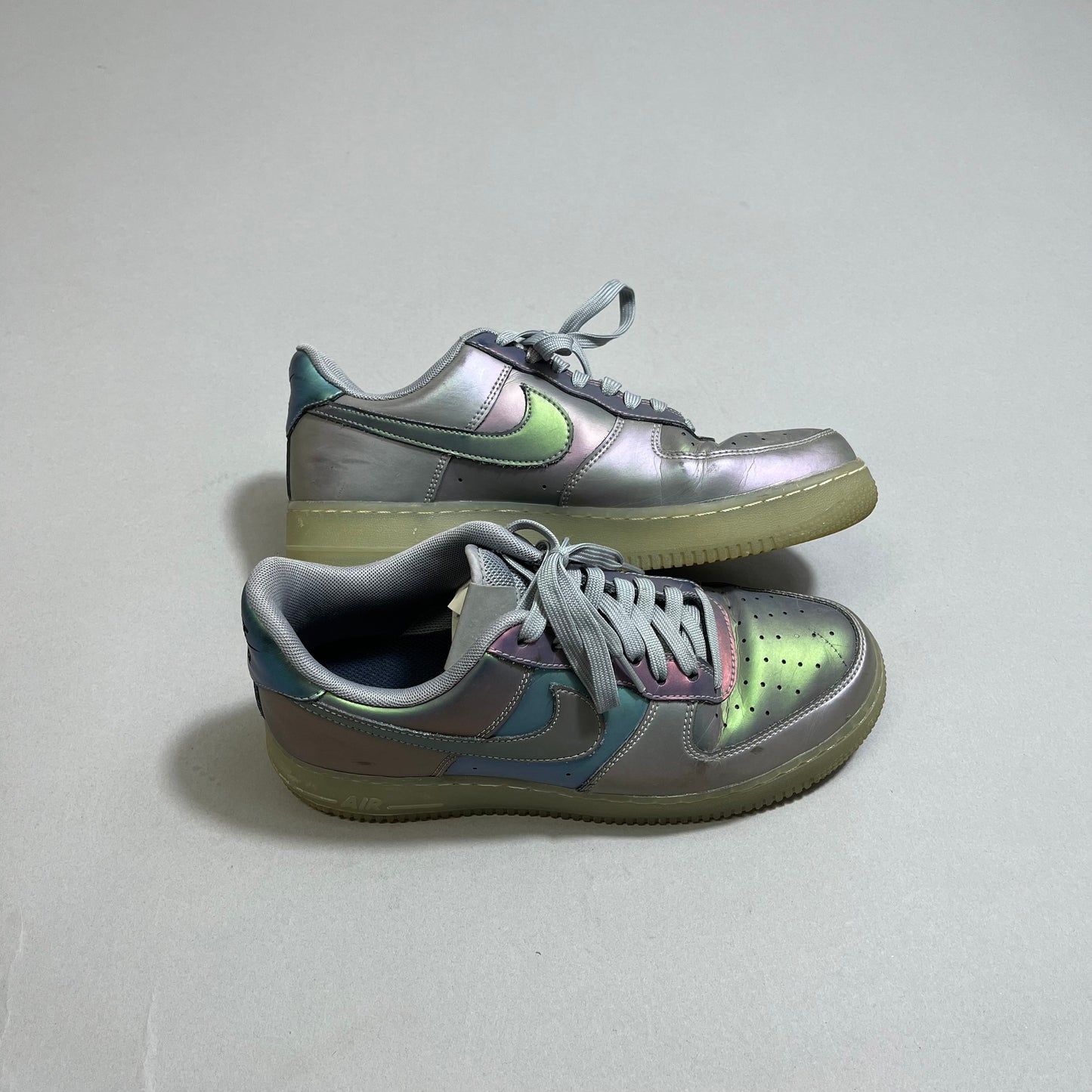 Holographic sneakers with grey laces on a plain background.