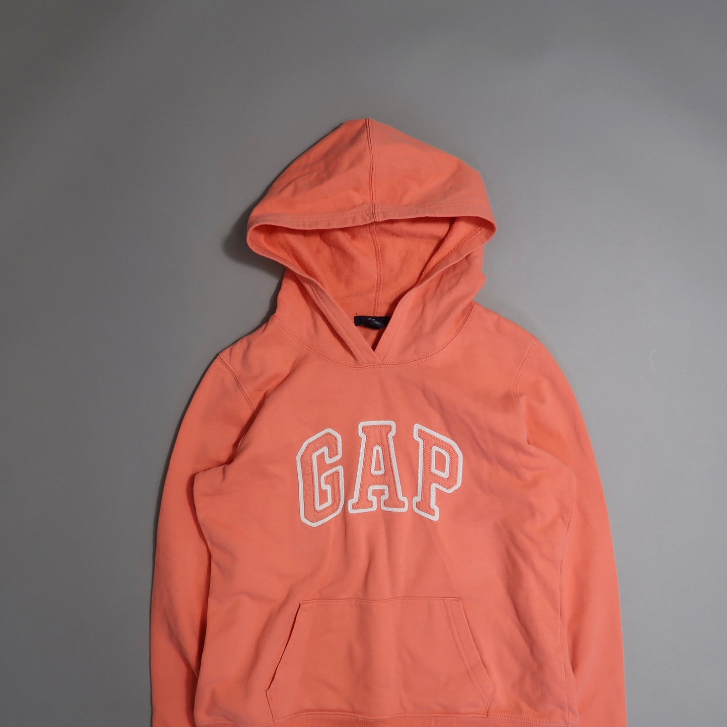 Orange GAP hoodie on a gray background.