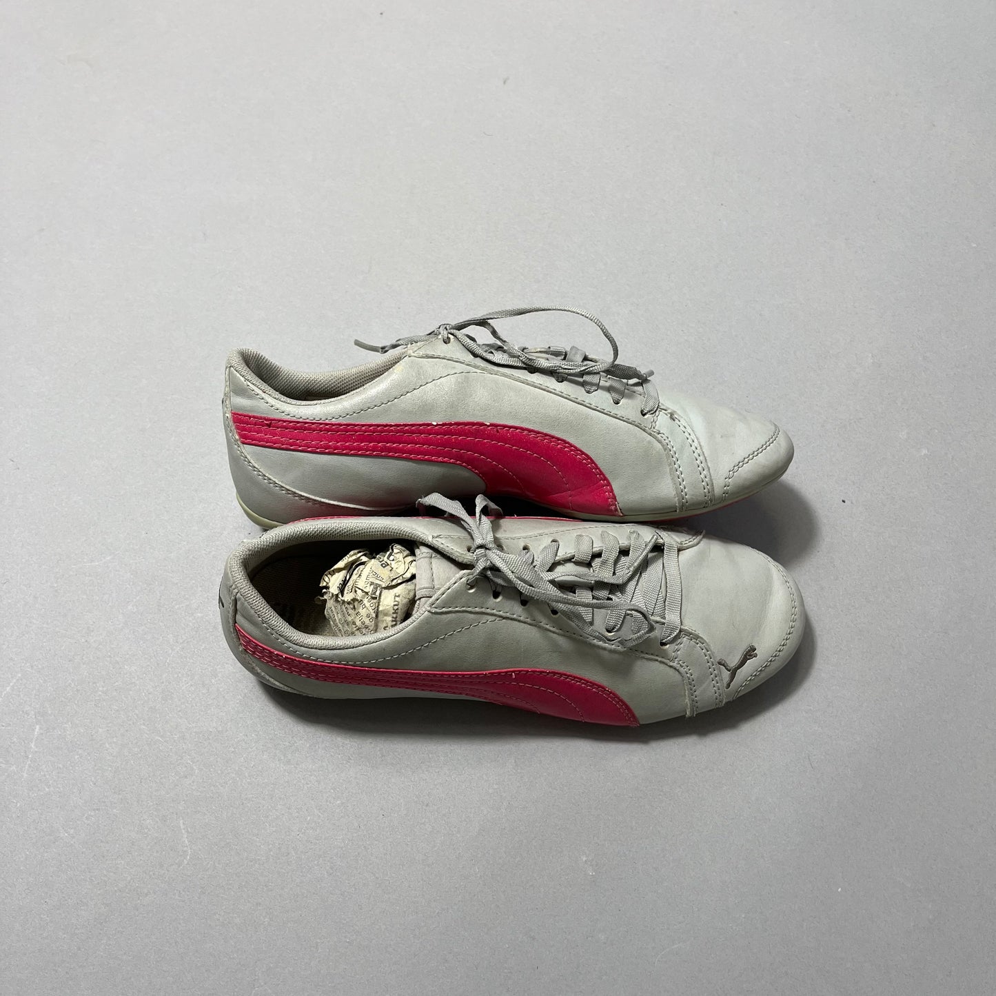 Gray sneakers with red stripes, one filled with paper, on a gray background.