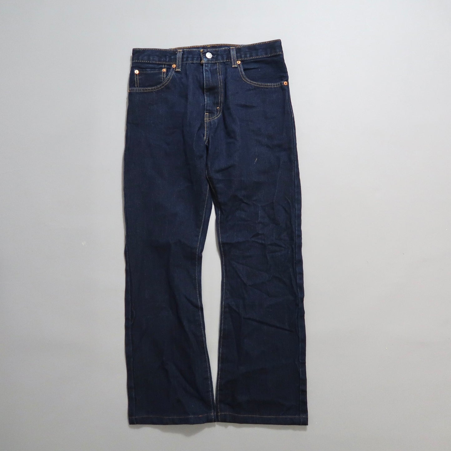 Dark blue denim jeans laid flat on a light gray background.