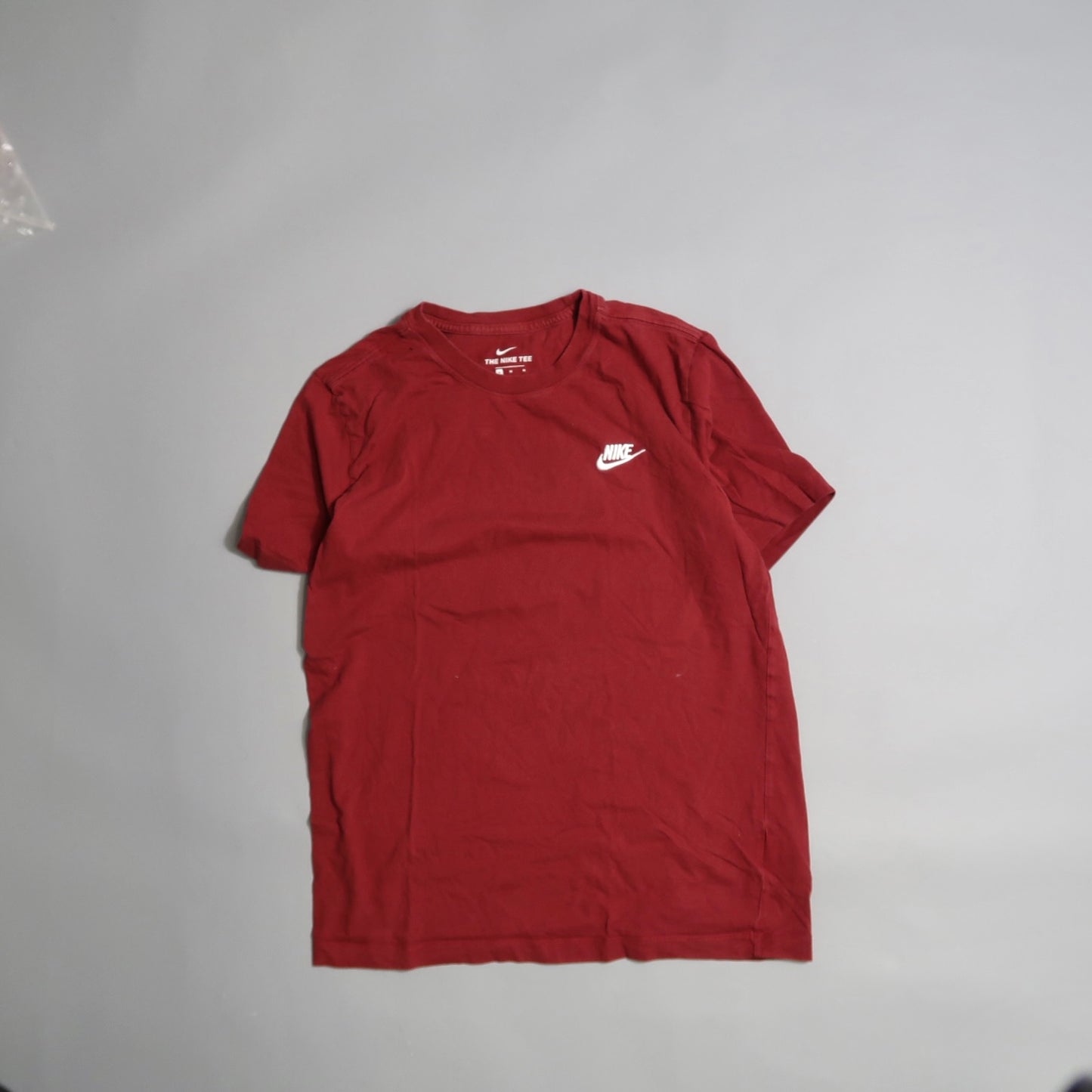 Red Nike T-shirt with a white logo on a plain background.