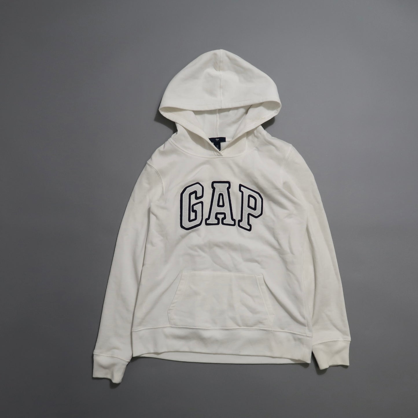 White GAP hoodie on a gray background.