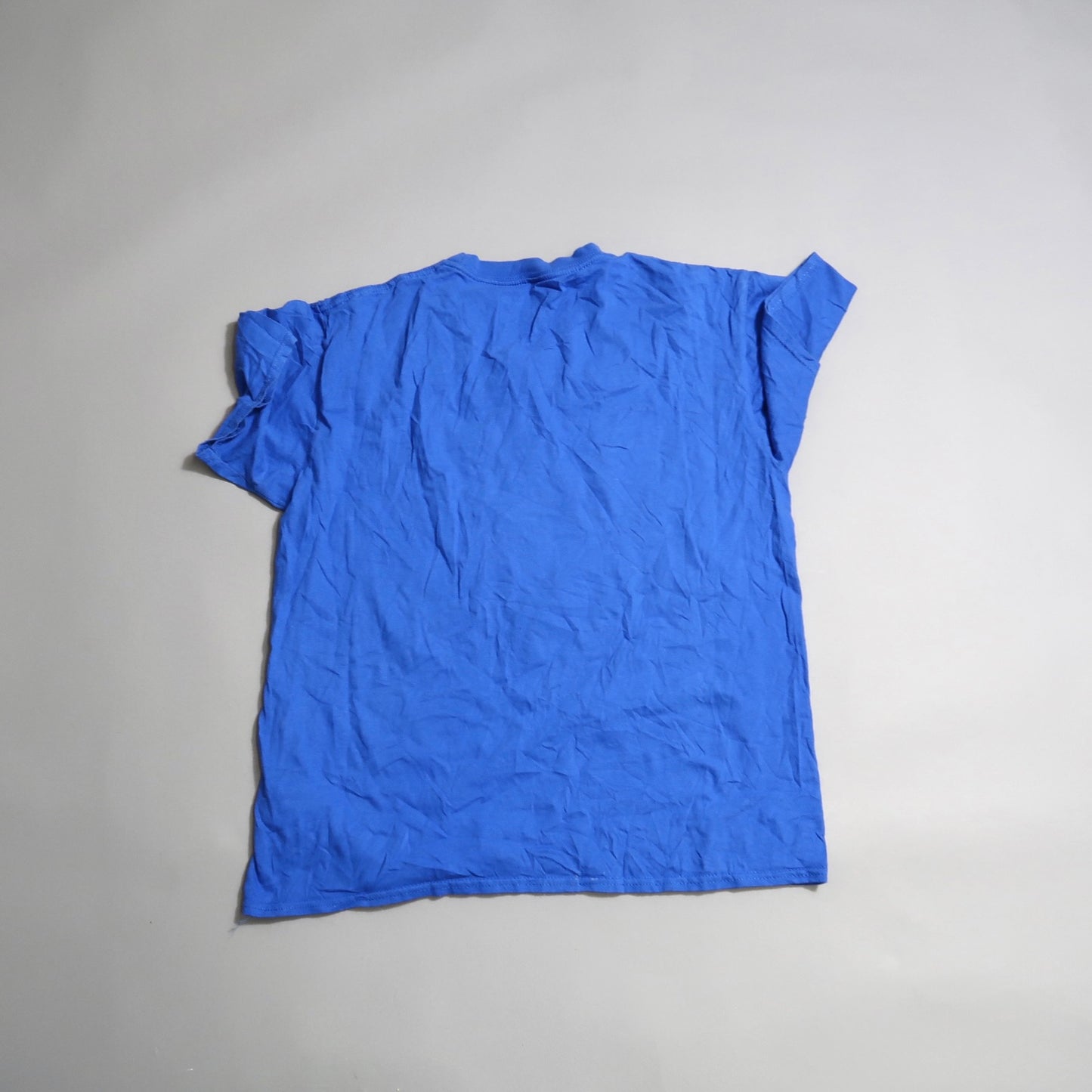 Wrinkled blue t-shirt laid flat on a neutral background.