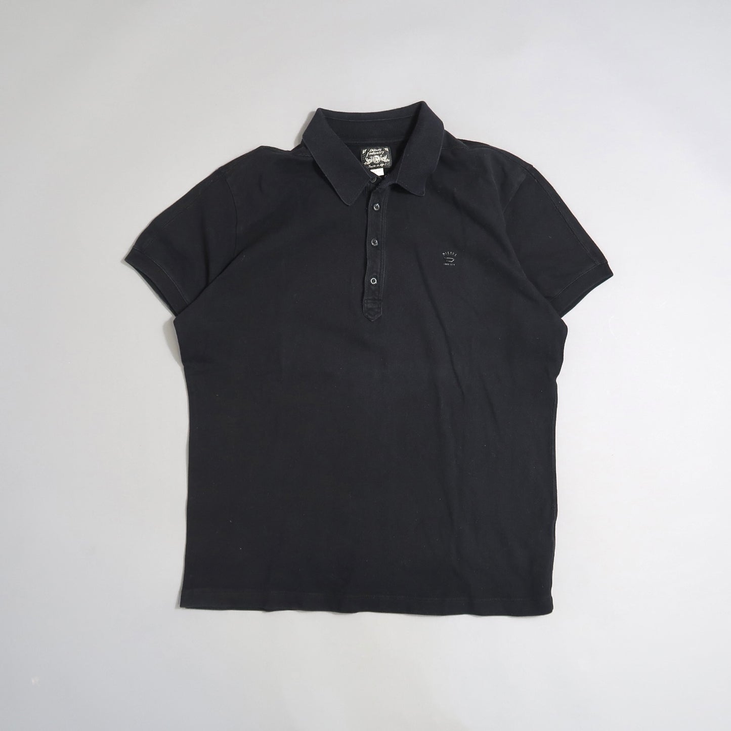 Black polo shirt with collar and short sleeves on a plain background.