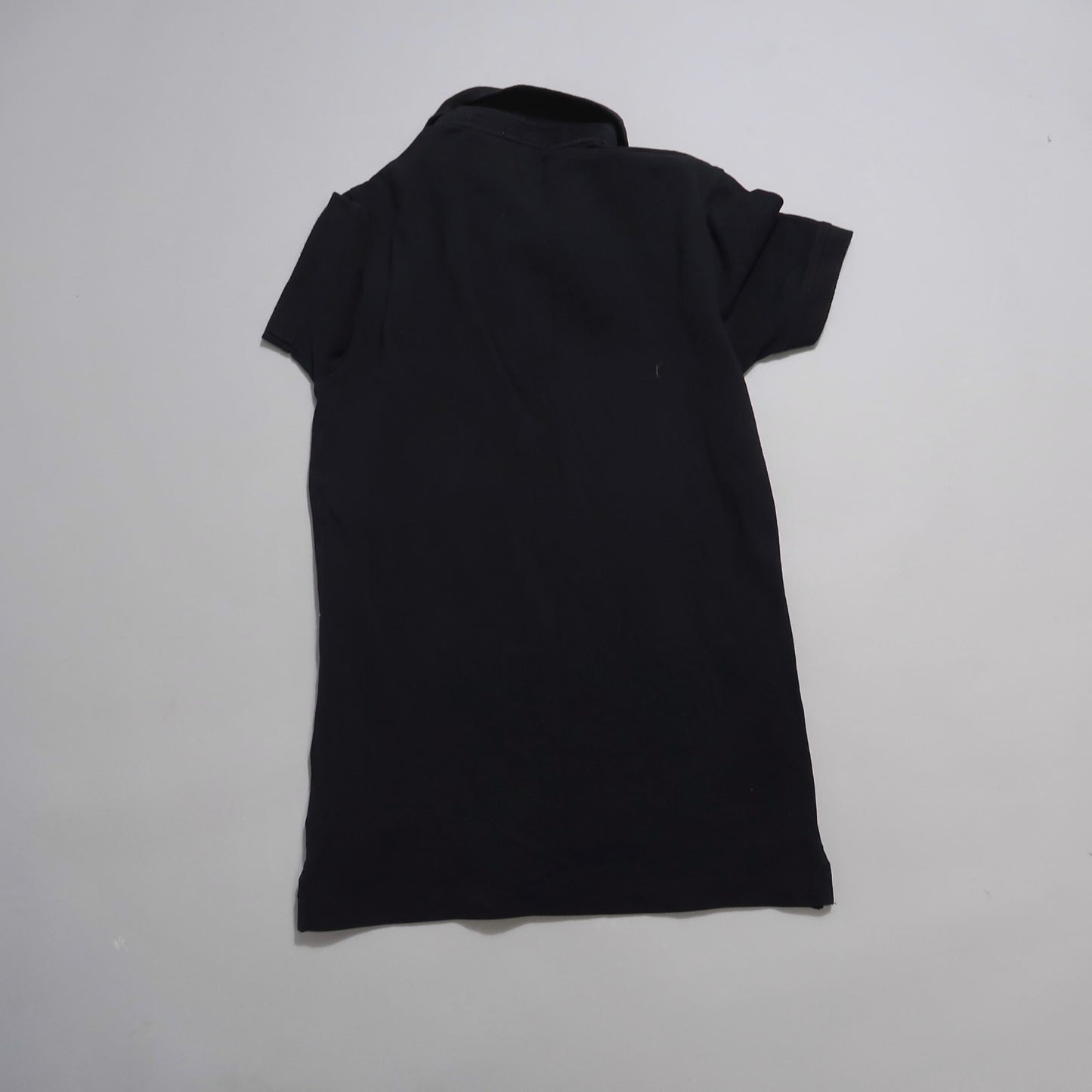 Black polo shirt laid flat on a plain background.