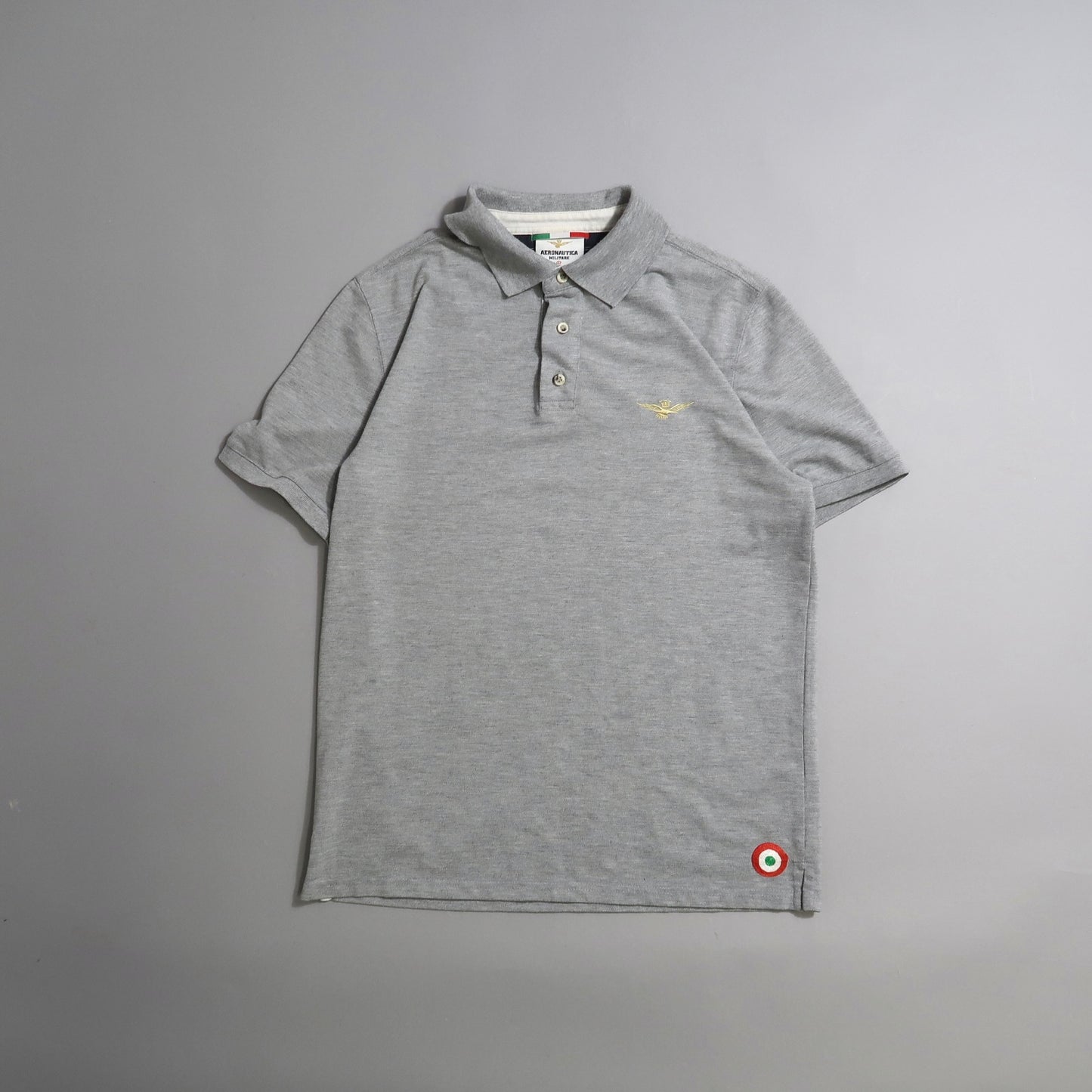 Gray polo shirt with small embroidery and button-up collar.
