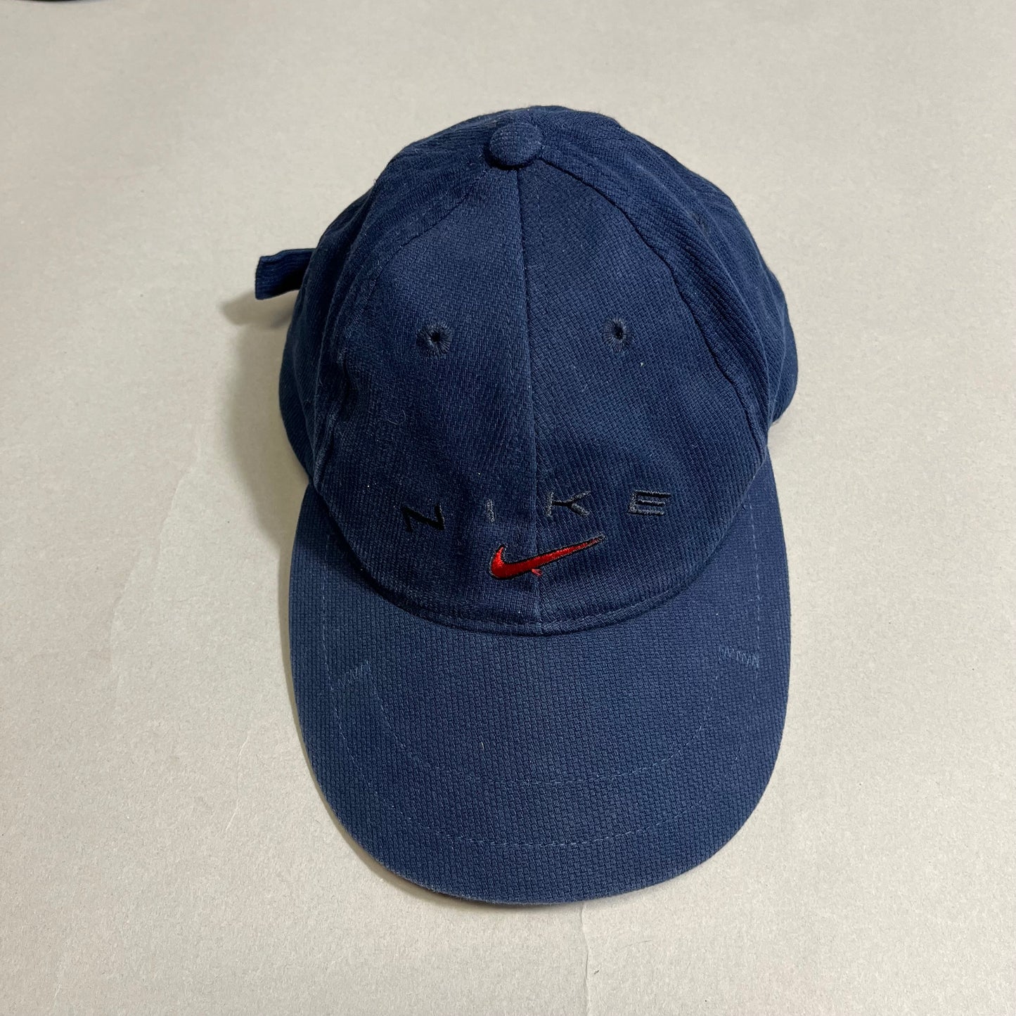 Blue Nike cap with a red logo on a neutral background.