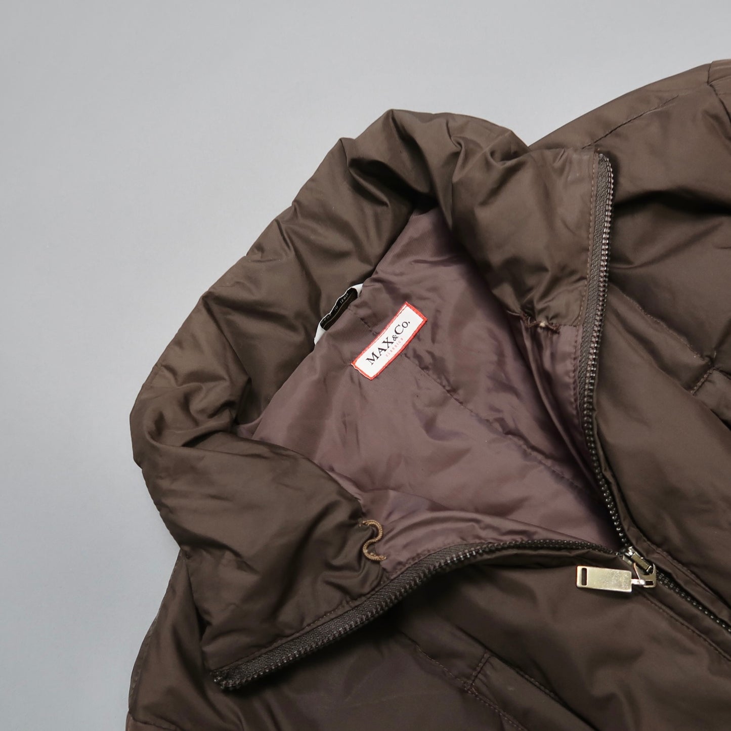 Close-up of brown puffer jacket with visible MAX&Co label.