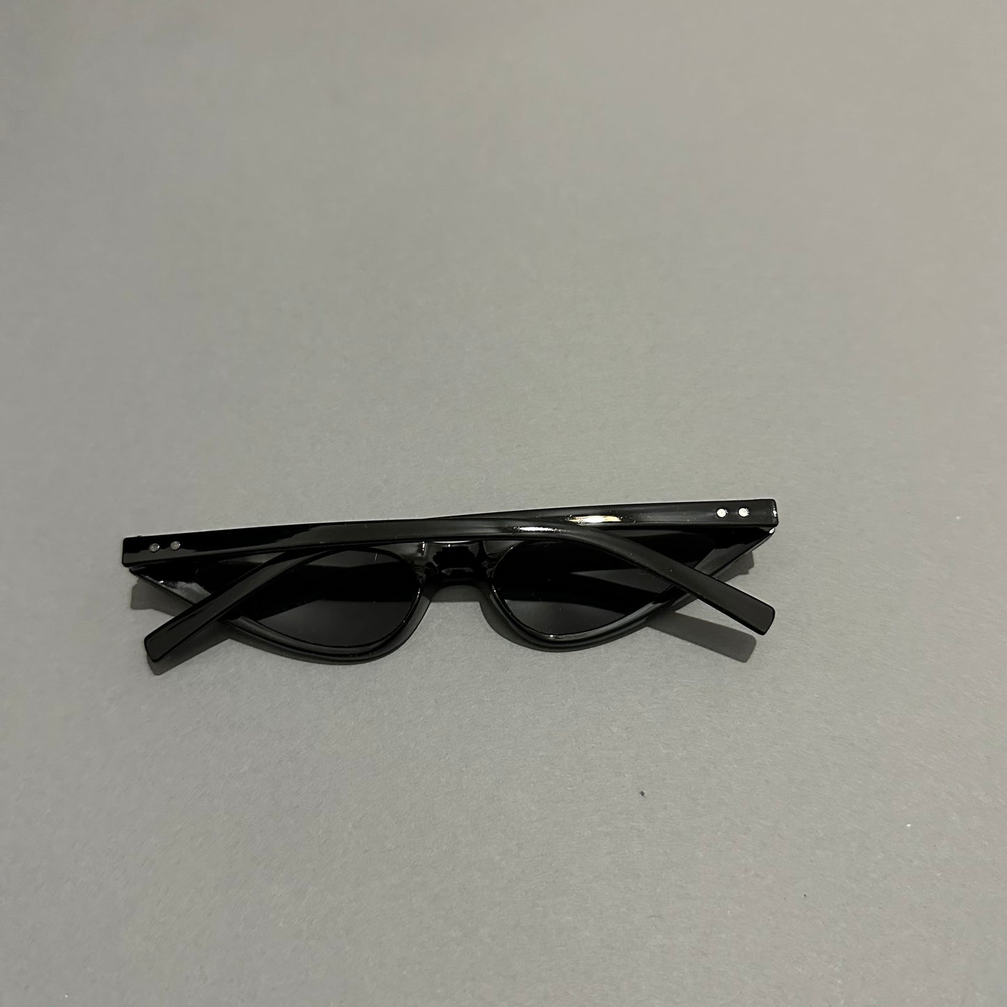 Black sunglasses folded on a gray surface.