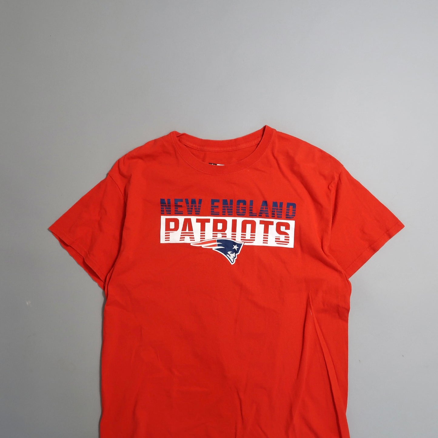 Red T-shirt with nullNew England Patriotsnull logo and text.