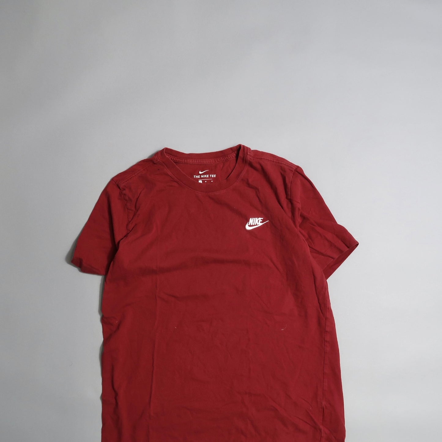 Red Nike T-shirt with logo displayed on a neutral background.