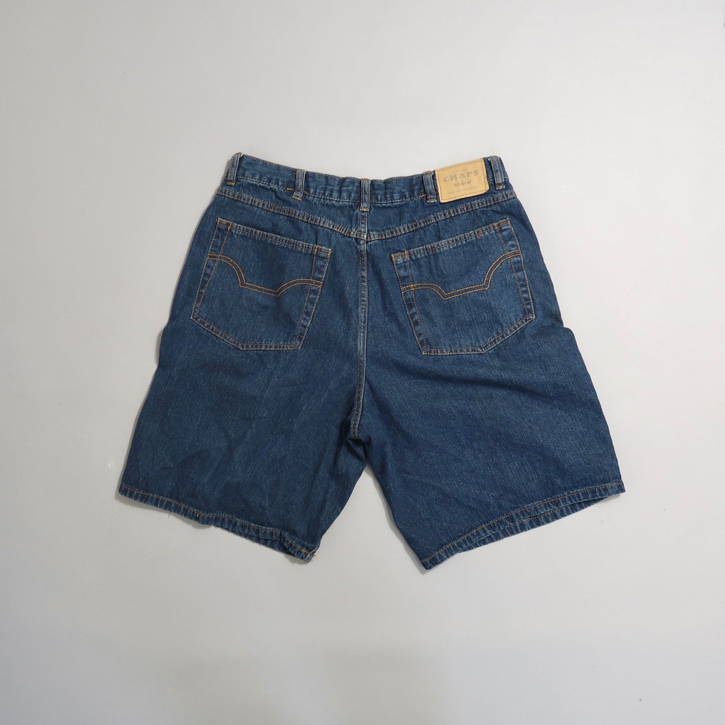 Denim shorts with back pockets and a leather patch on a white background.