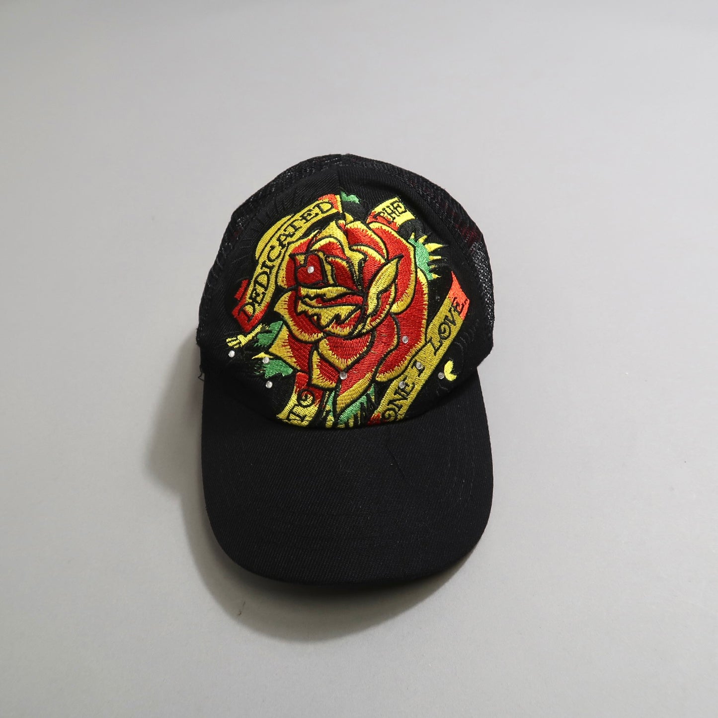 Black cap with a vibrant embroidered rose design and text.