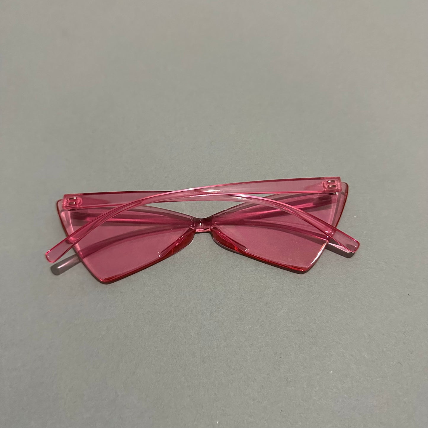 Pink angular sunglasses on a gray surface.