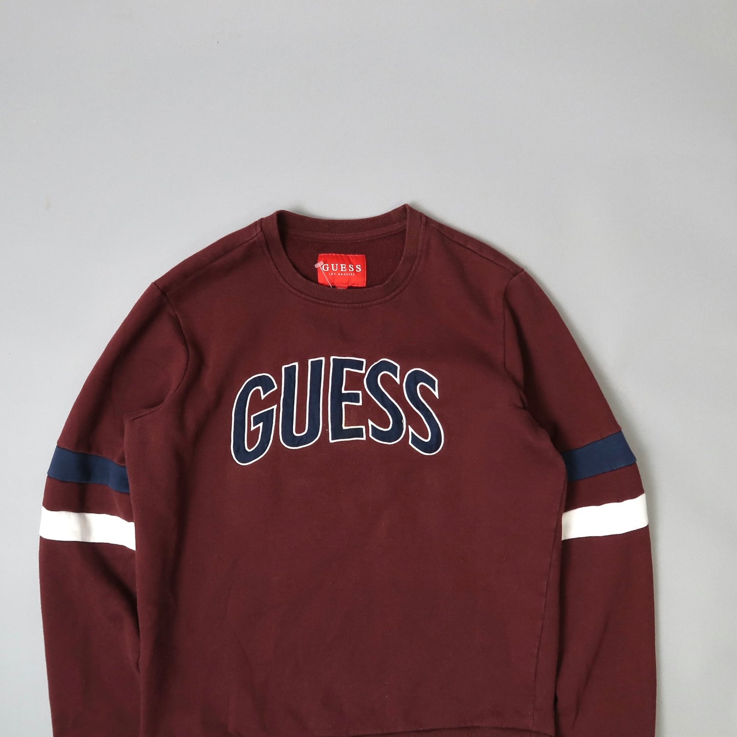 Burgundy Guess sweatshirt with navy and white sleeve stripes.