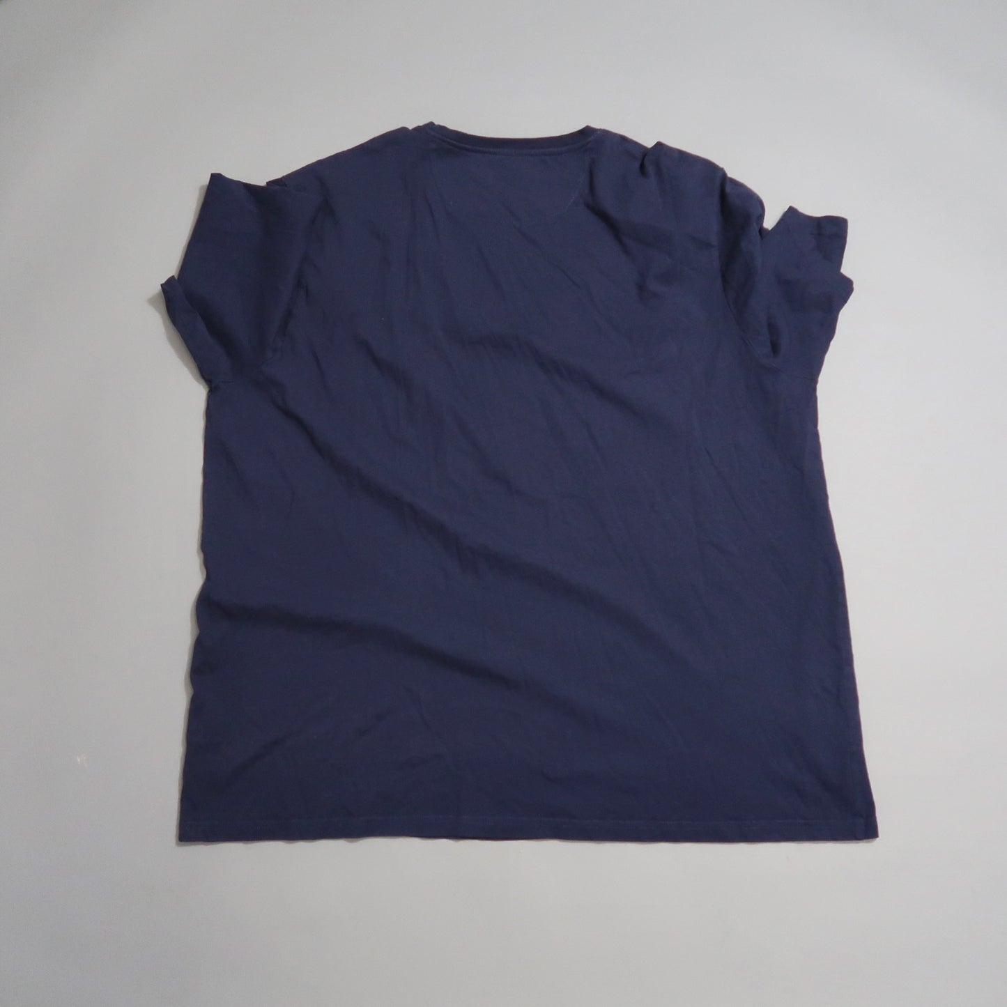 Back view of a dark blue T-shirt on a light surface.