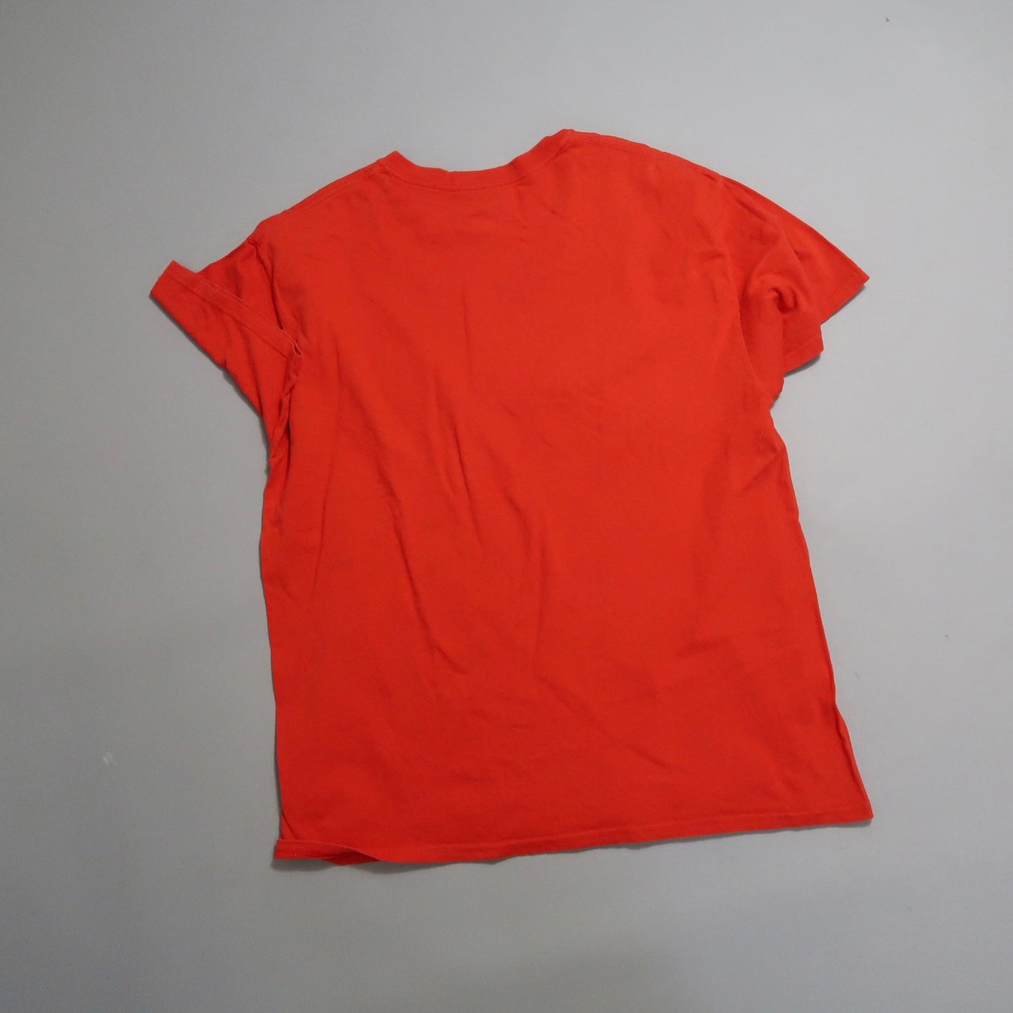 Red t-shirt laid flat on a light gray surface.