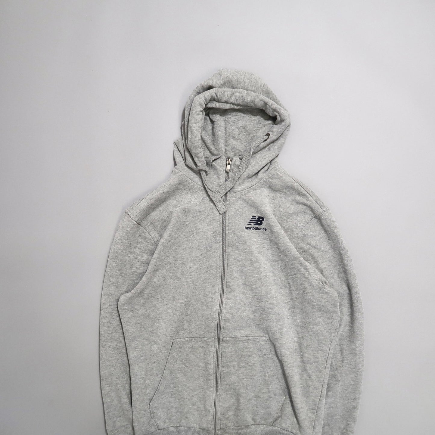 Gray New Balance hoodie with a zipper, laid flat on a white background.