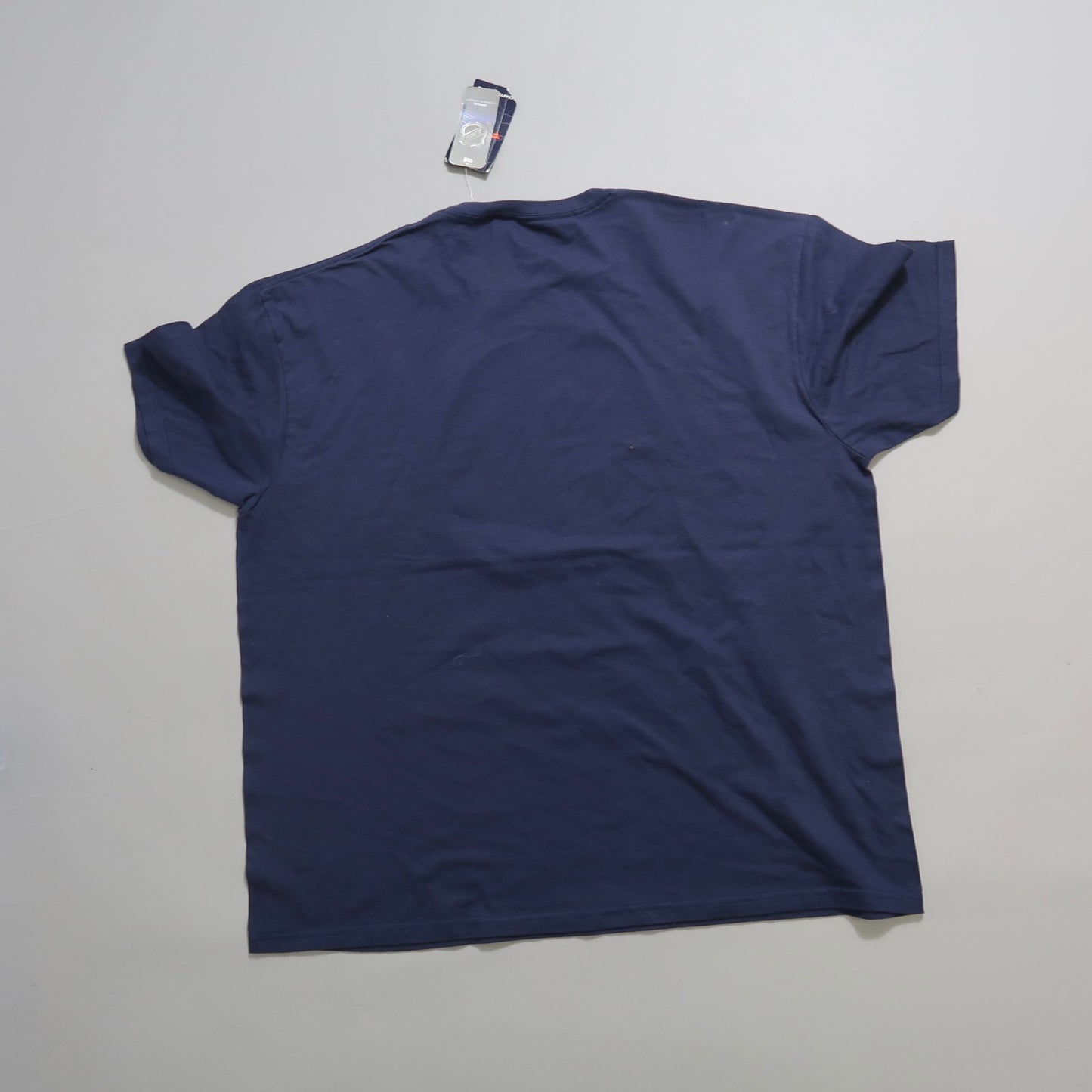 Back view of a plain navy T-shirt on a light surface.