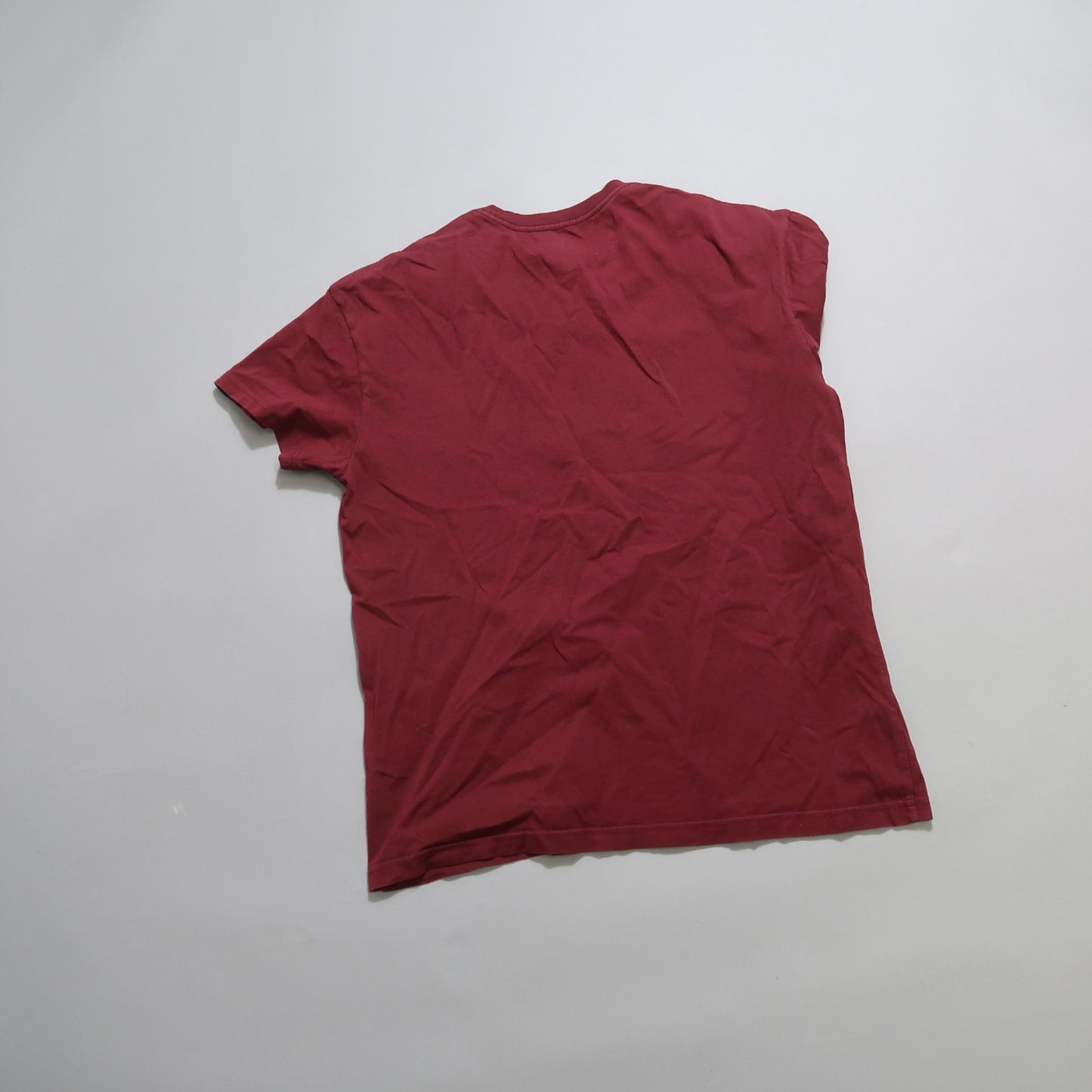 Crumpled red T-shirt lying flat on a plain background.