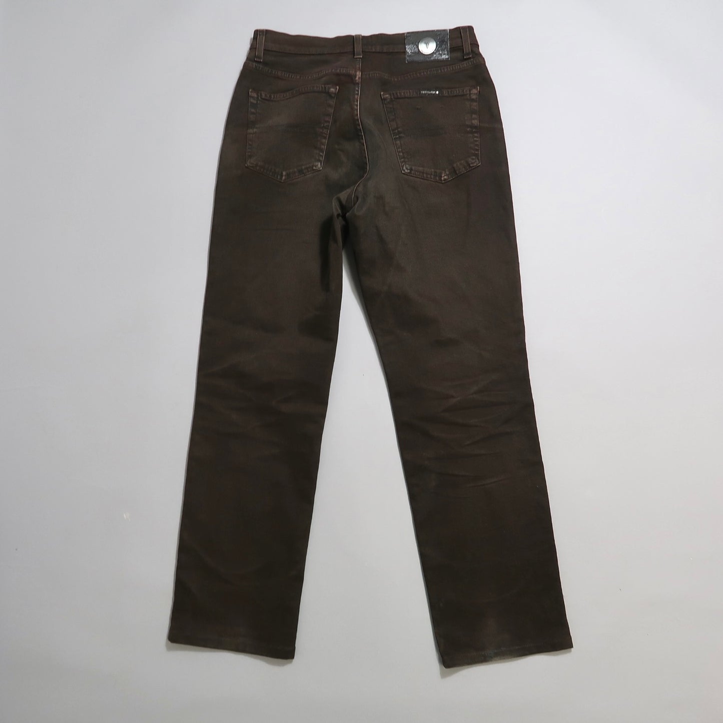 Brown jeans laid flat, showing back pockets and stitching.