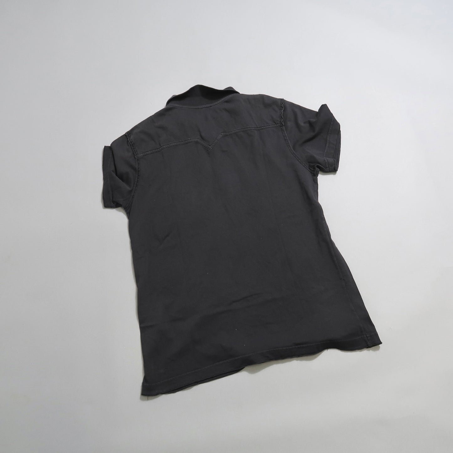 Back view of a short-sleeved dark shirt on a light background.