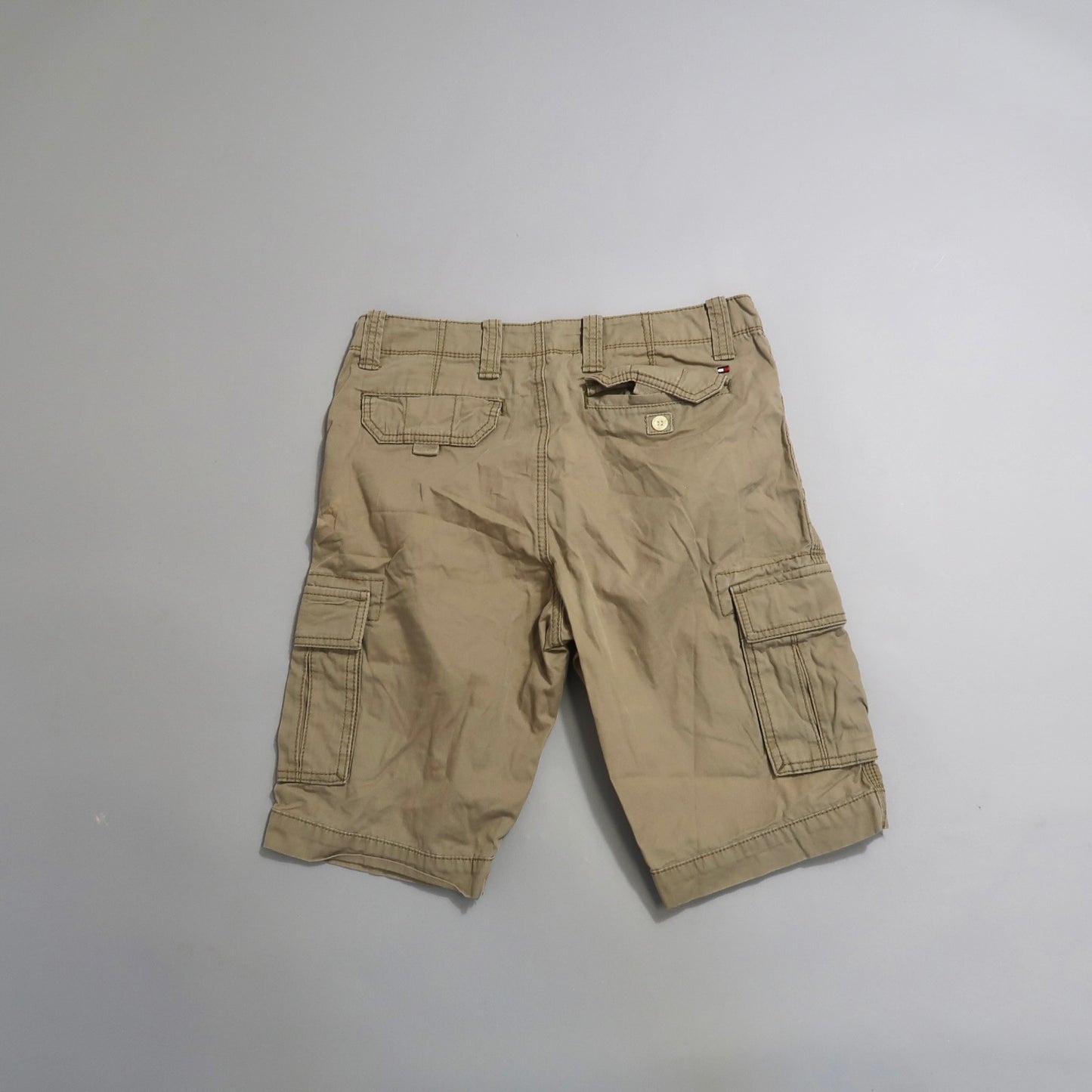 Khaki cargo shorts with multiple pockets on a light background.